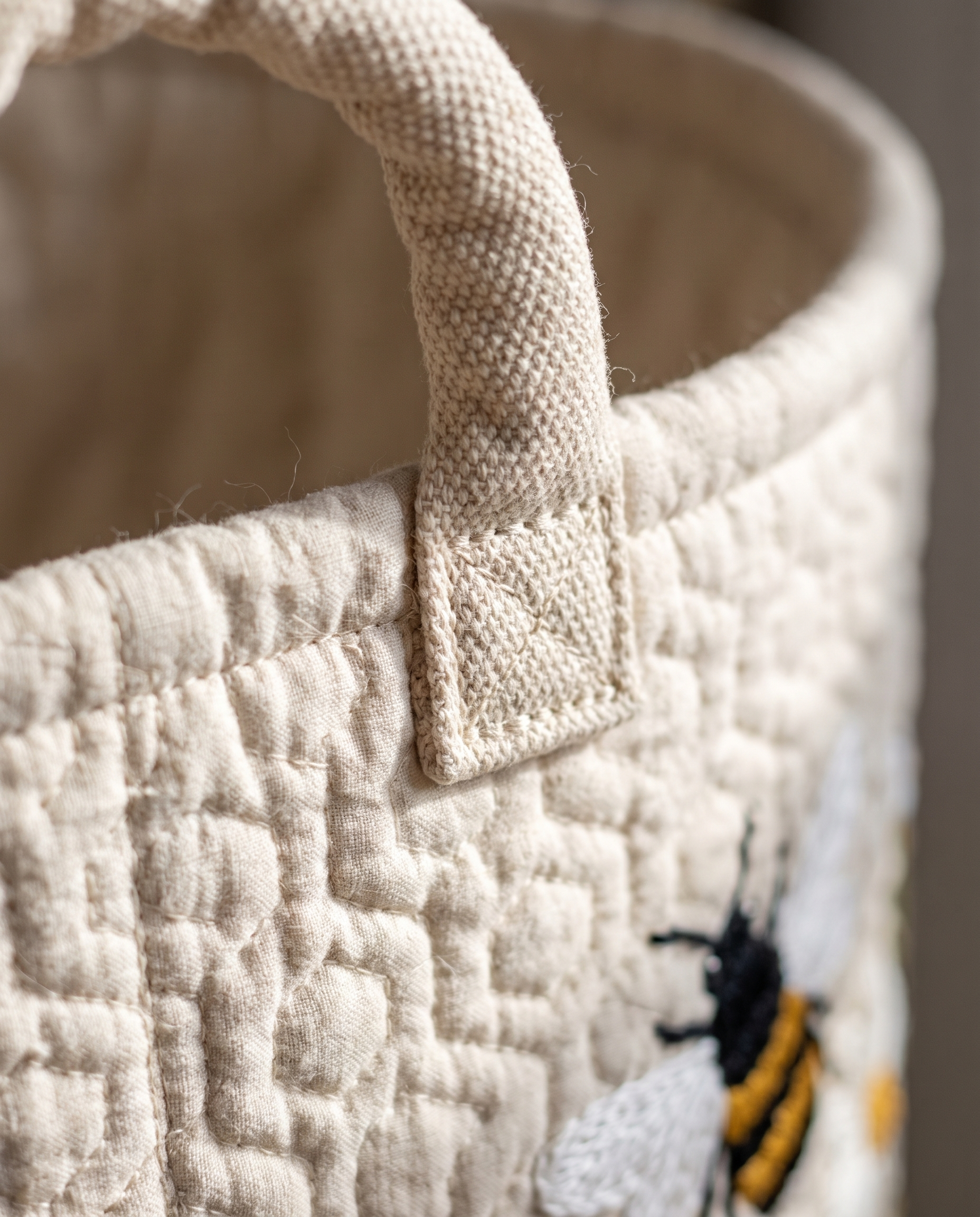 Close-up detail of the Evely Rose Daisy Bee laundry basket's quilted texture and canvas handle stitching