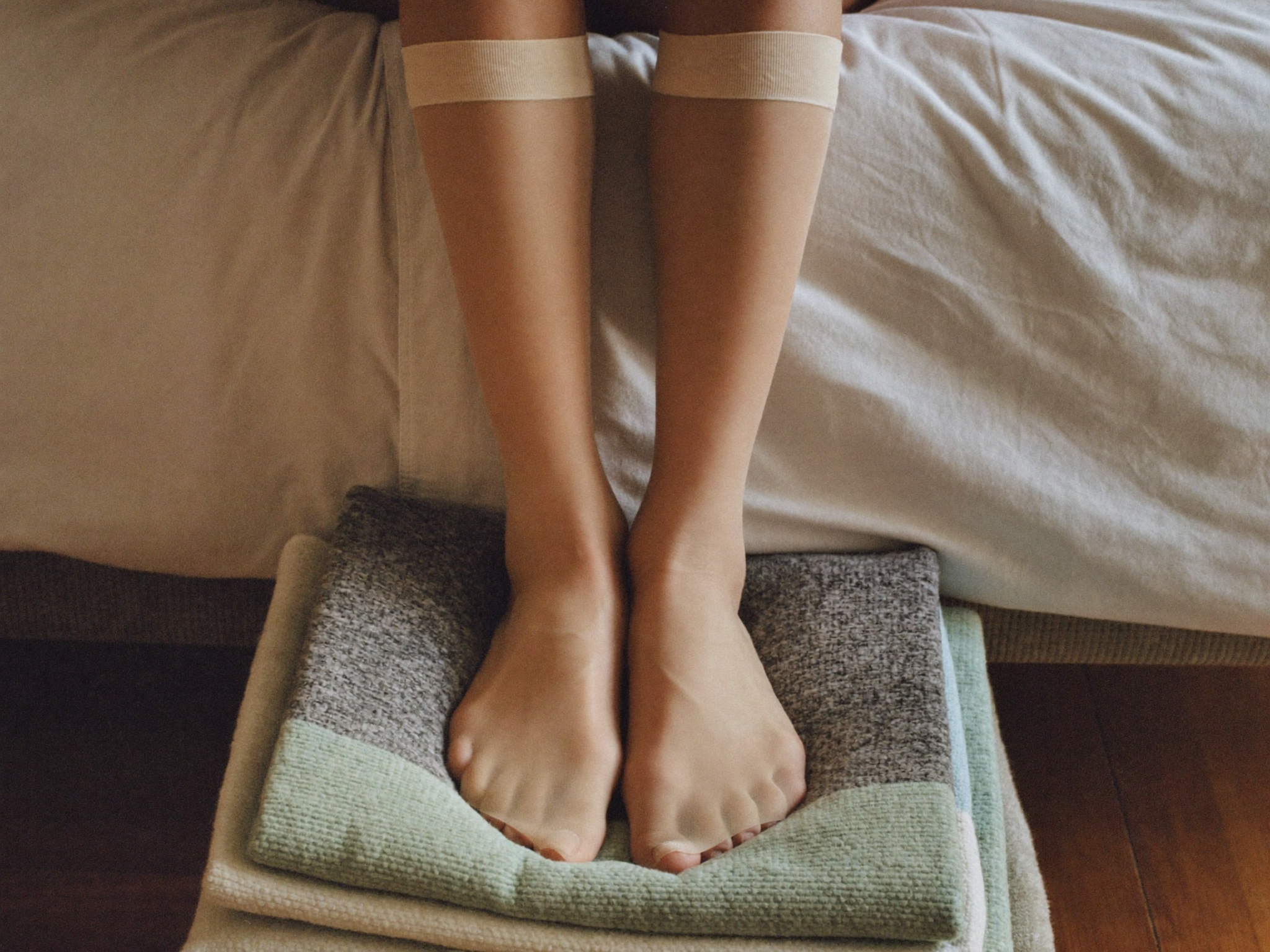 Legs wearing firm compression stockings, elevated on a cushion