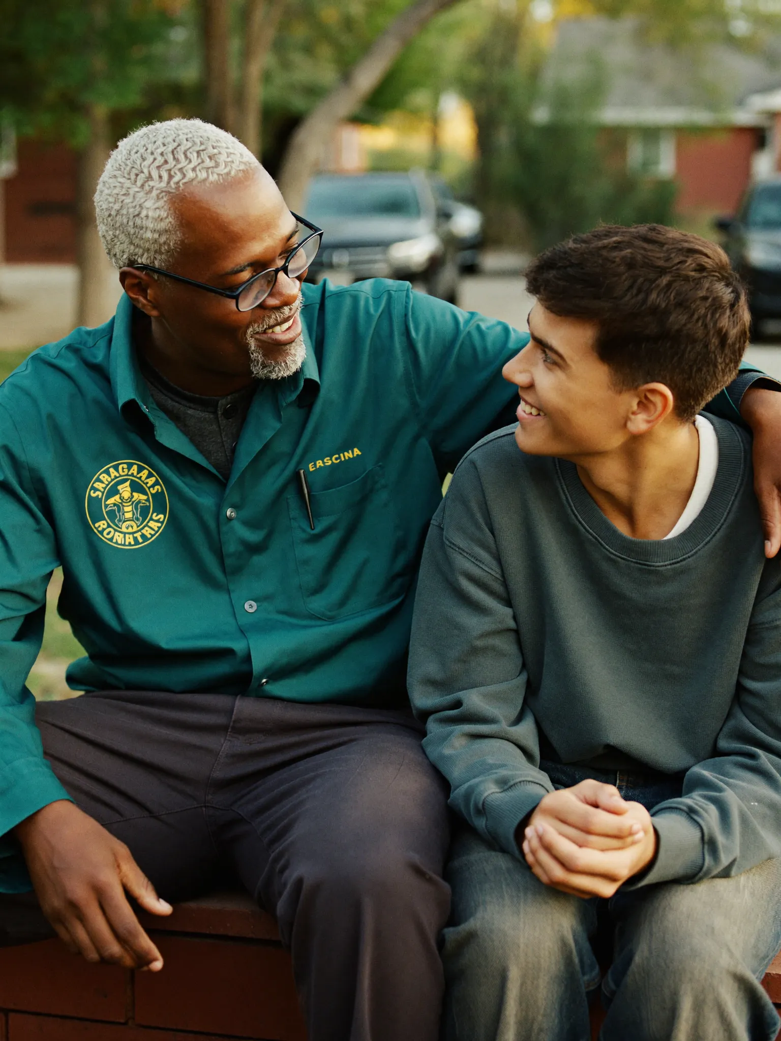 A mentor and a teenager talking and smiling outdoors