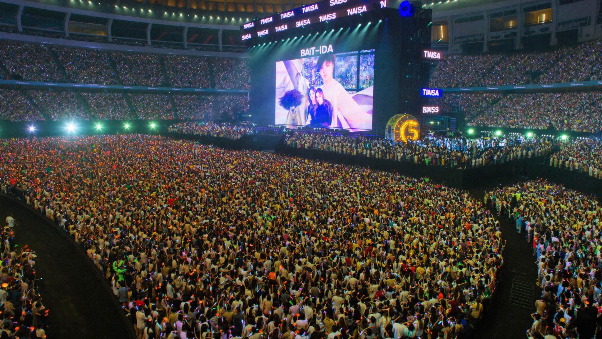 K-pop concert in Southeast Asia with colorful light sticks and diverse audience