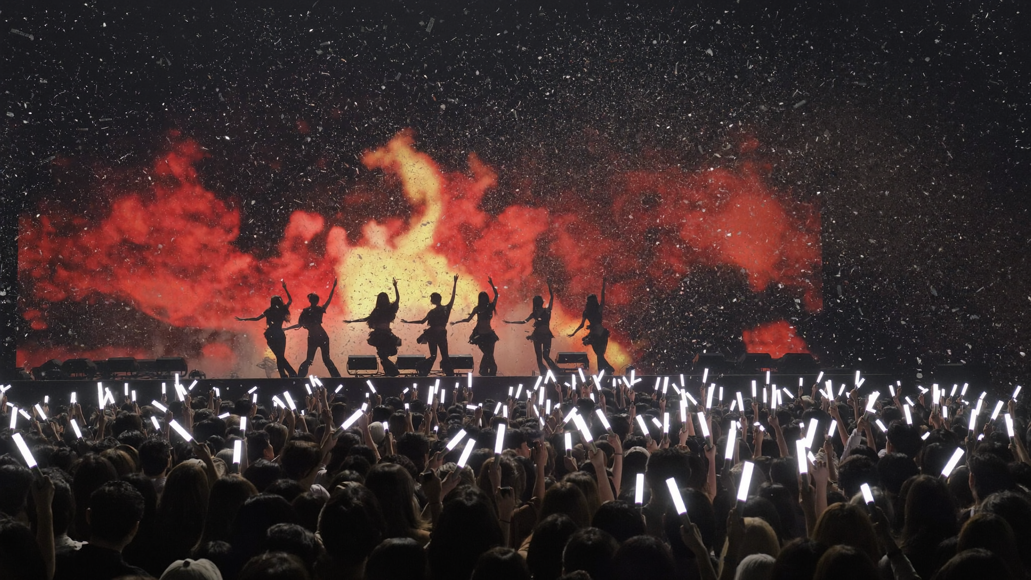 K-pop concert crowd with light sticks celebrating a girl group release like KATSEYE Animal
