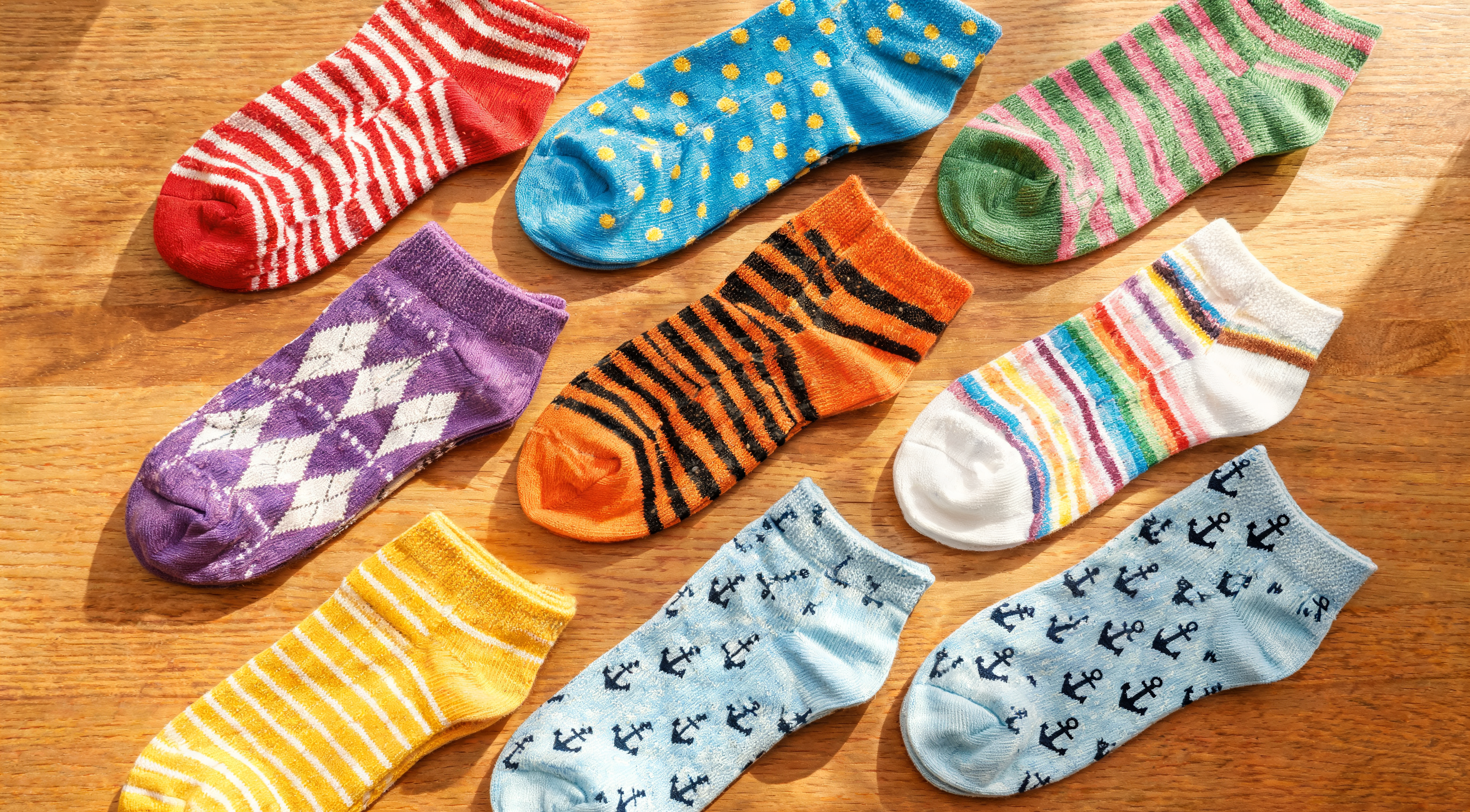 A neat flat lay of colorful striped and patterned socks arranged on a wooden table