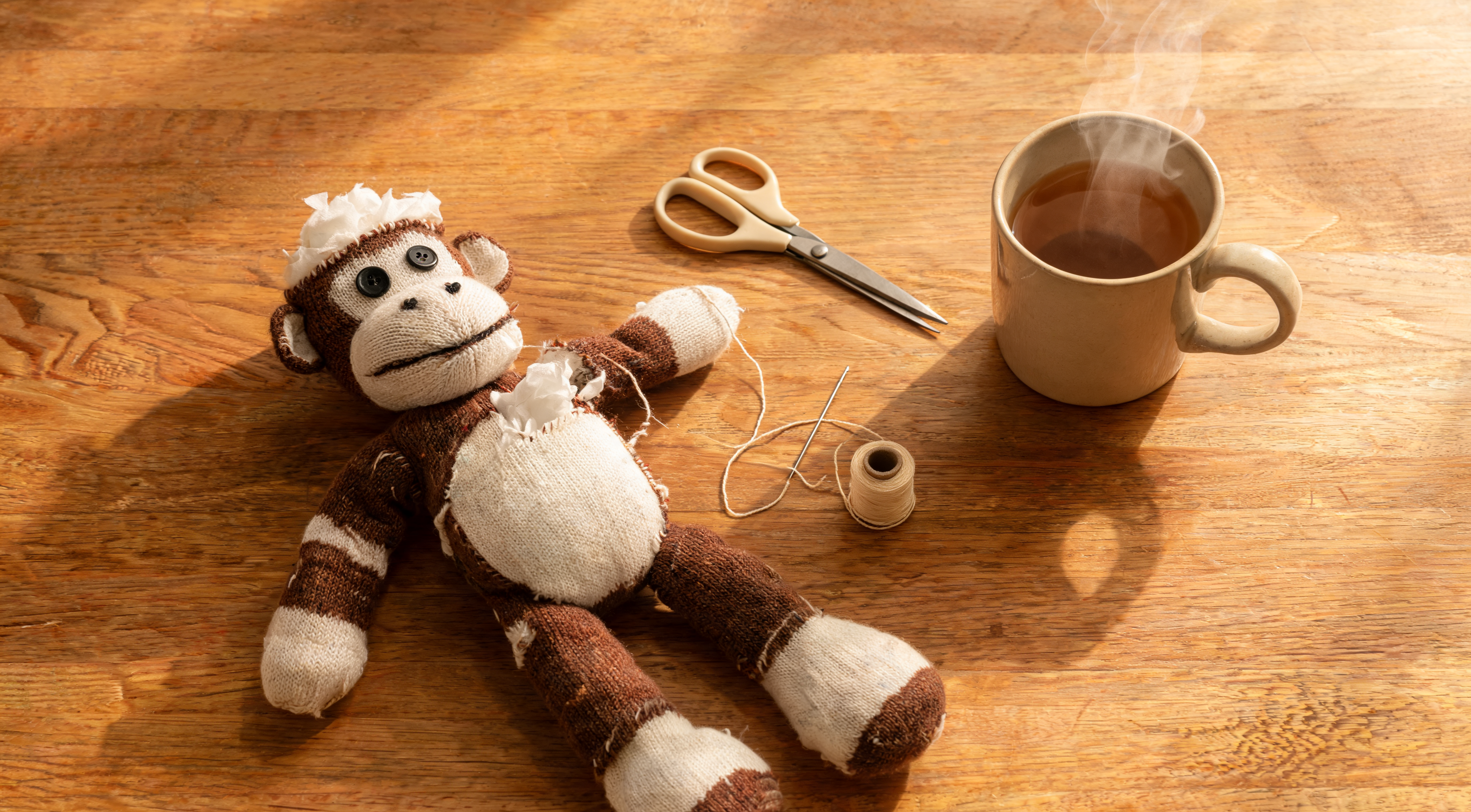 A cozy craft workspace with a half-finished sock monkey, a needle and thread, scissors, and a cup of tea