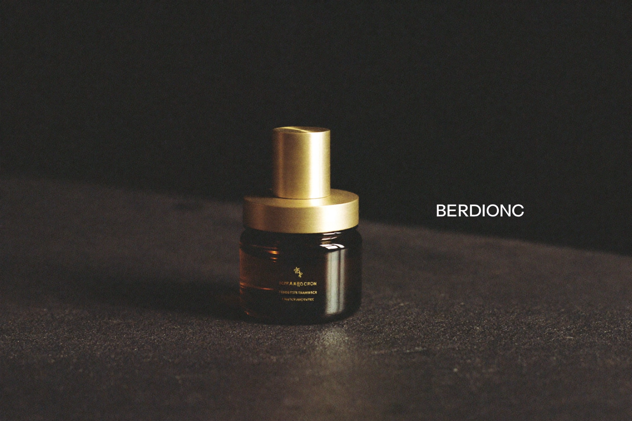 A single amber-glass peptide vial with a brushed gold cap on a matte black surface.