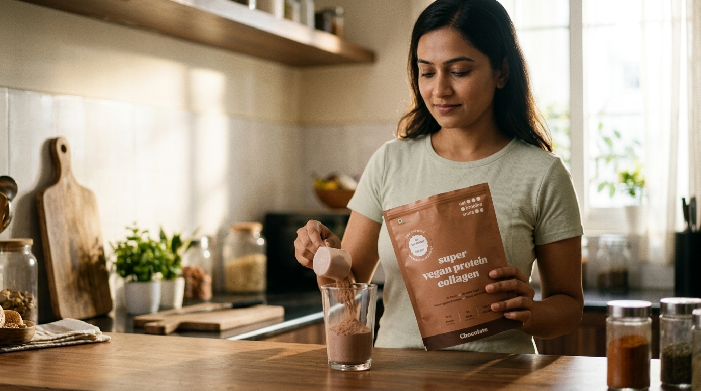 Indian woman holding the Super Vegan Protein Collagen Chocolate pouch and pouring a scoop into a glass at her kitchen counter, comfortable and content