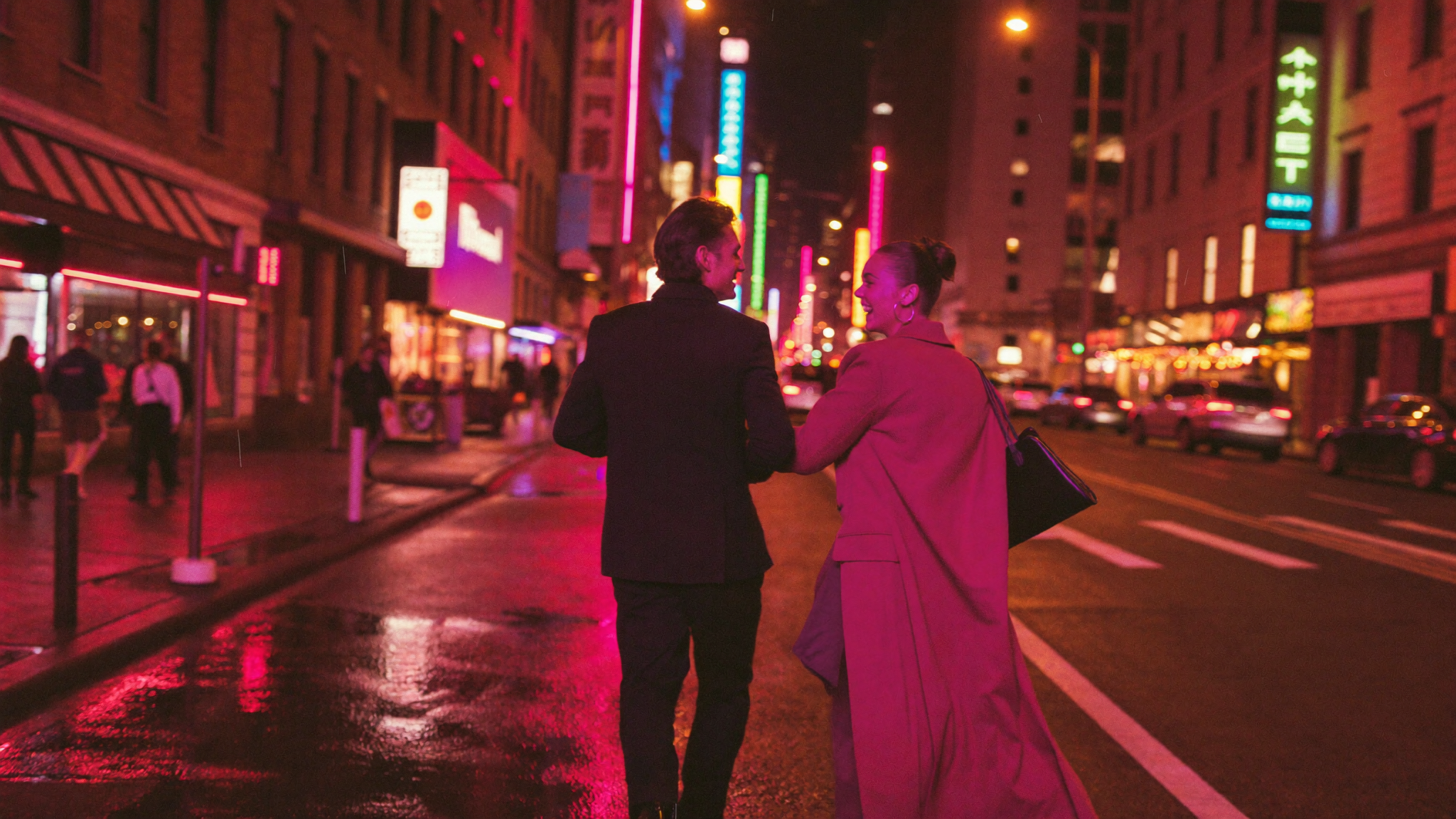 Couple walking on a neon-lit city street at night