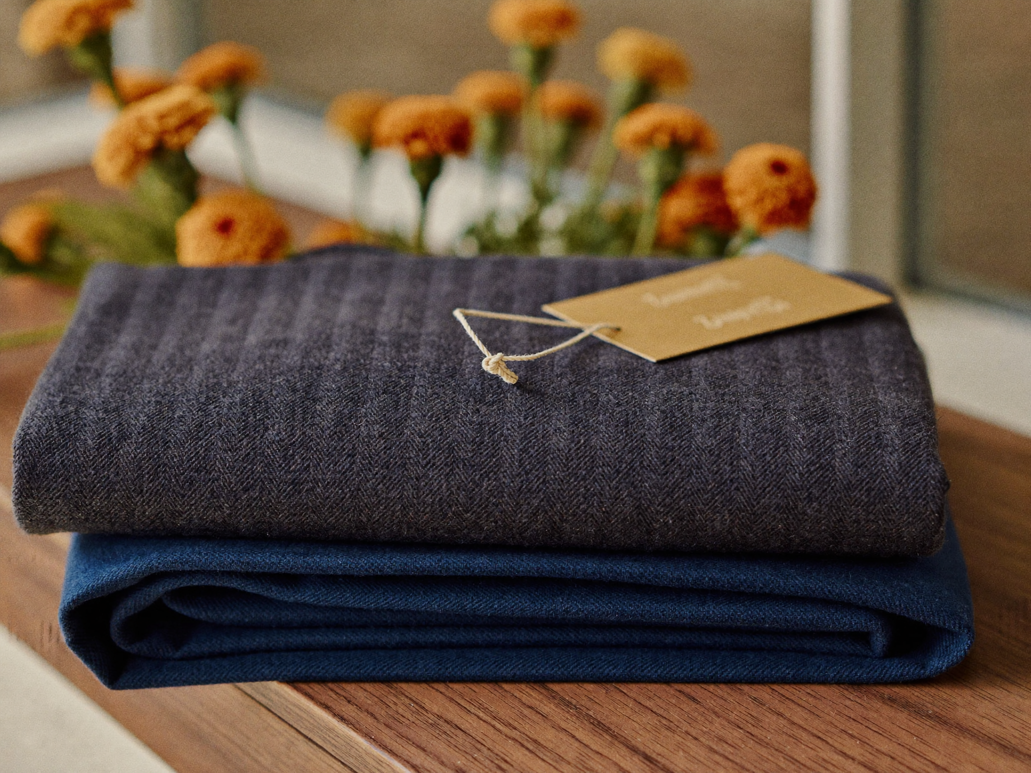 Two folded lengths of premium wool suiting fabric with a small gift tag, ready to be gifted