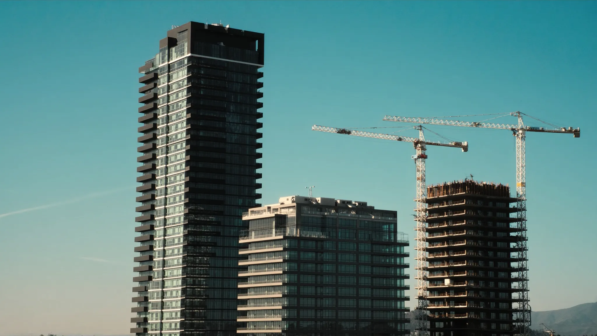 Construction cranes building new condo towers beside completed buildings in Etobicoke