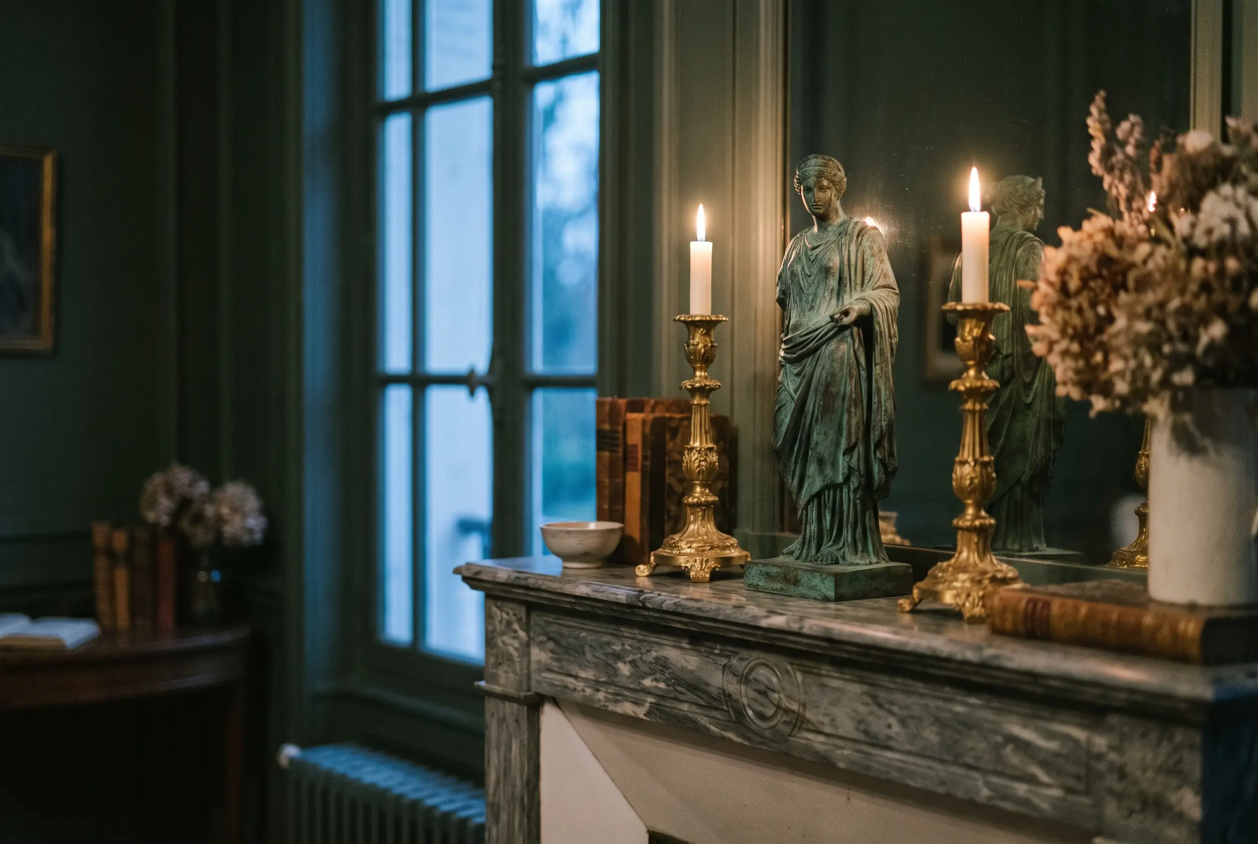 Statuette en bronze patiné et flambeaux dorés sur une cheminée en marbre