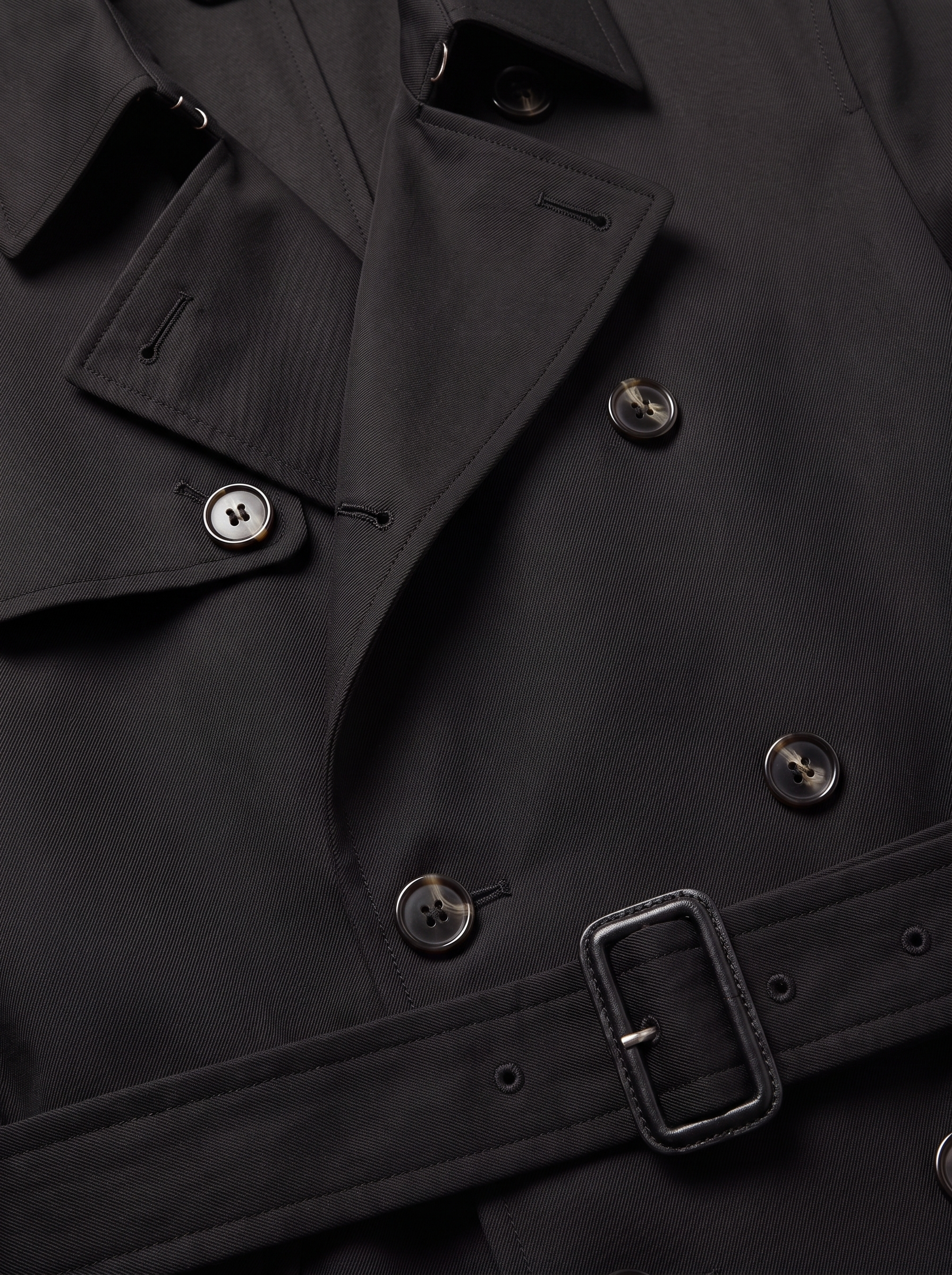 Black trench coat lapel button and belt close up detail
