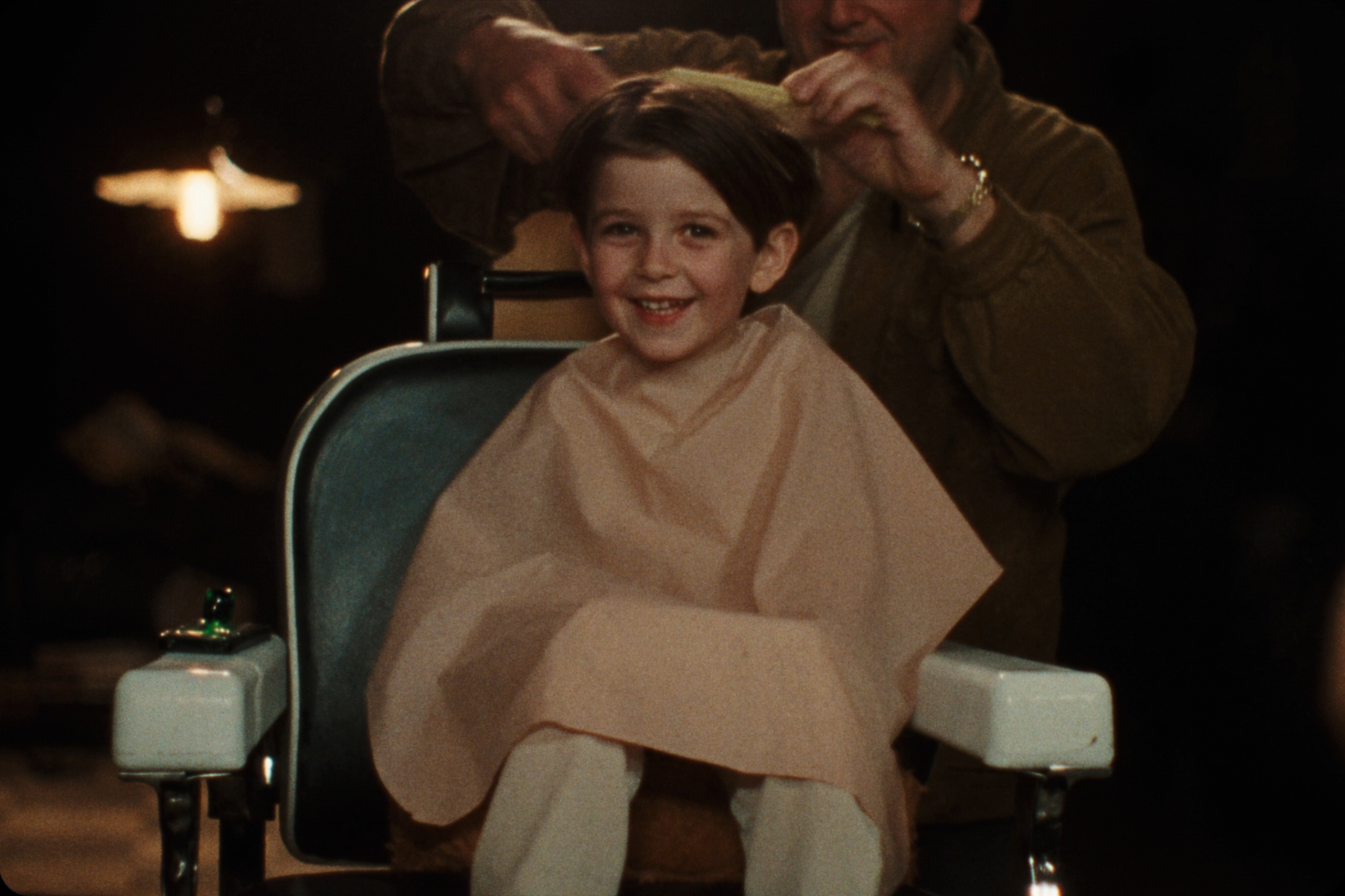 A young boy getting a kids' cut in the barber chair