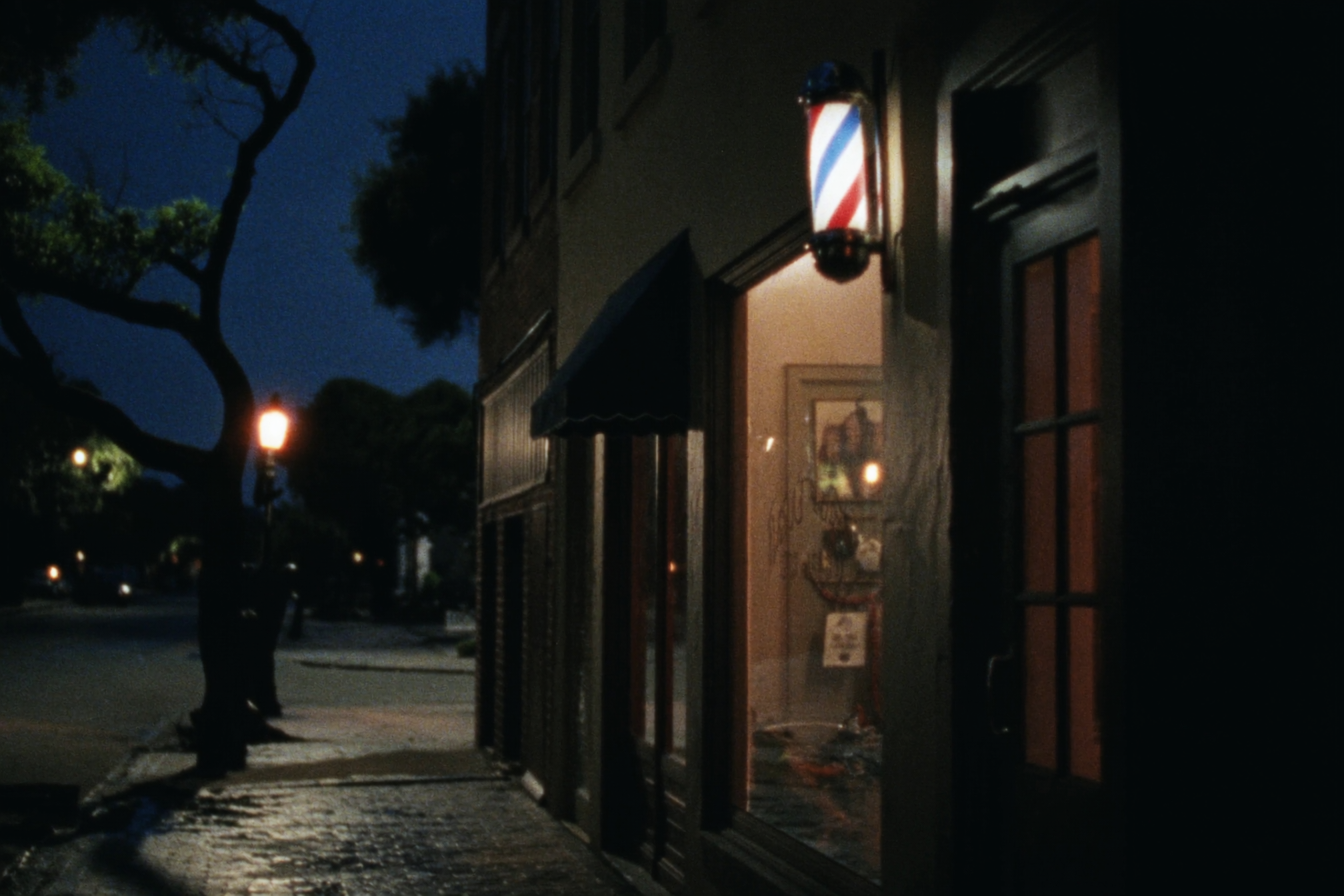 Ironwood Barber Co. storefront at dusk on a brick street with a spinning barber pole