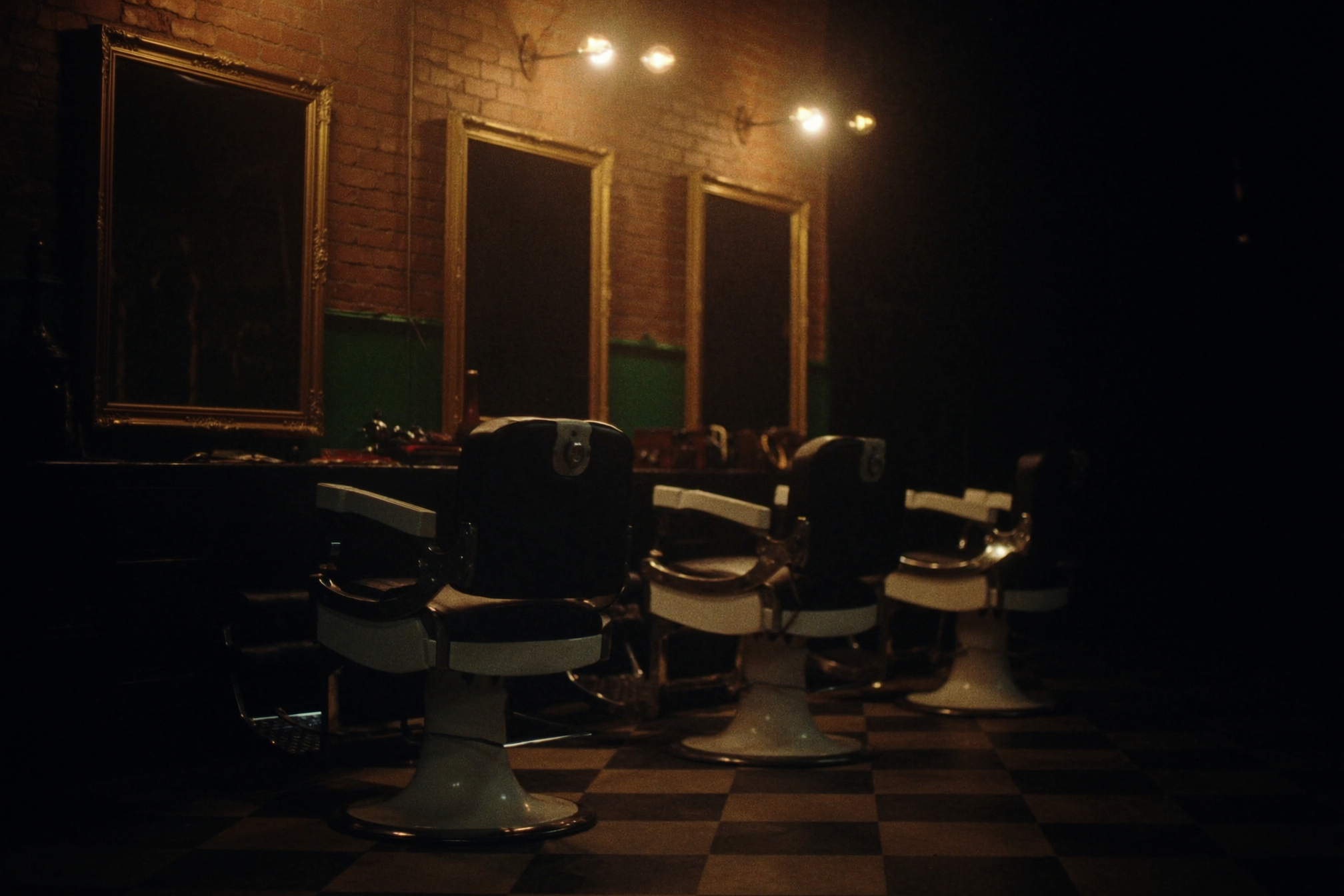 Interior of Ironwood Barber Co. — vintage leather barber chairs, exposed brick and warm Edison-bulb lighting