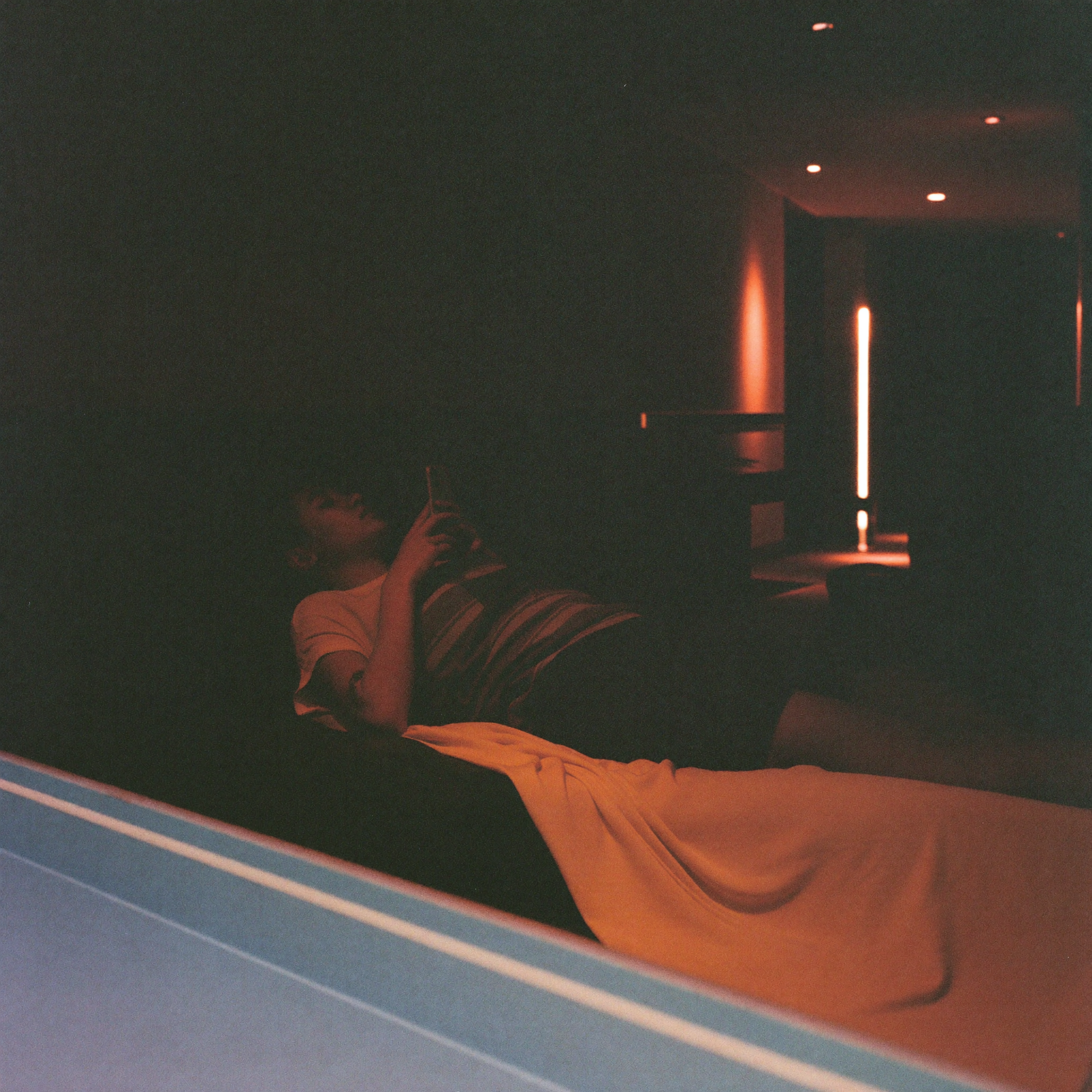 Person checking a phone before a float tank session in a dim spa hallway