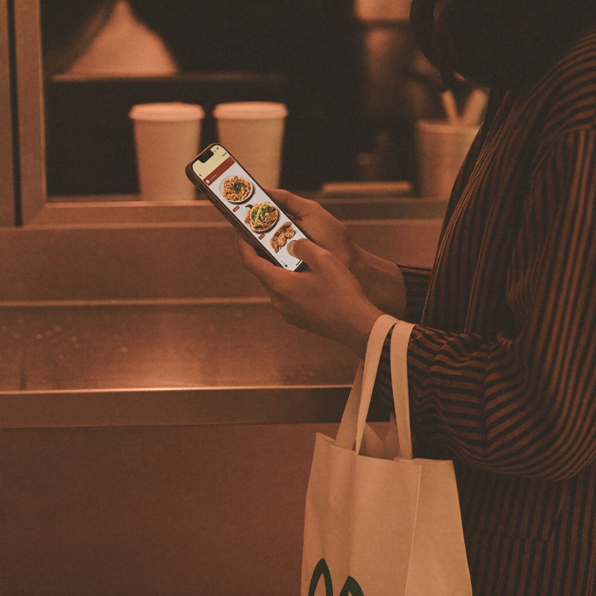 Customer picking up a mobile order at a fast food counter, phone in hand