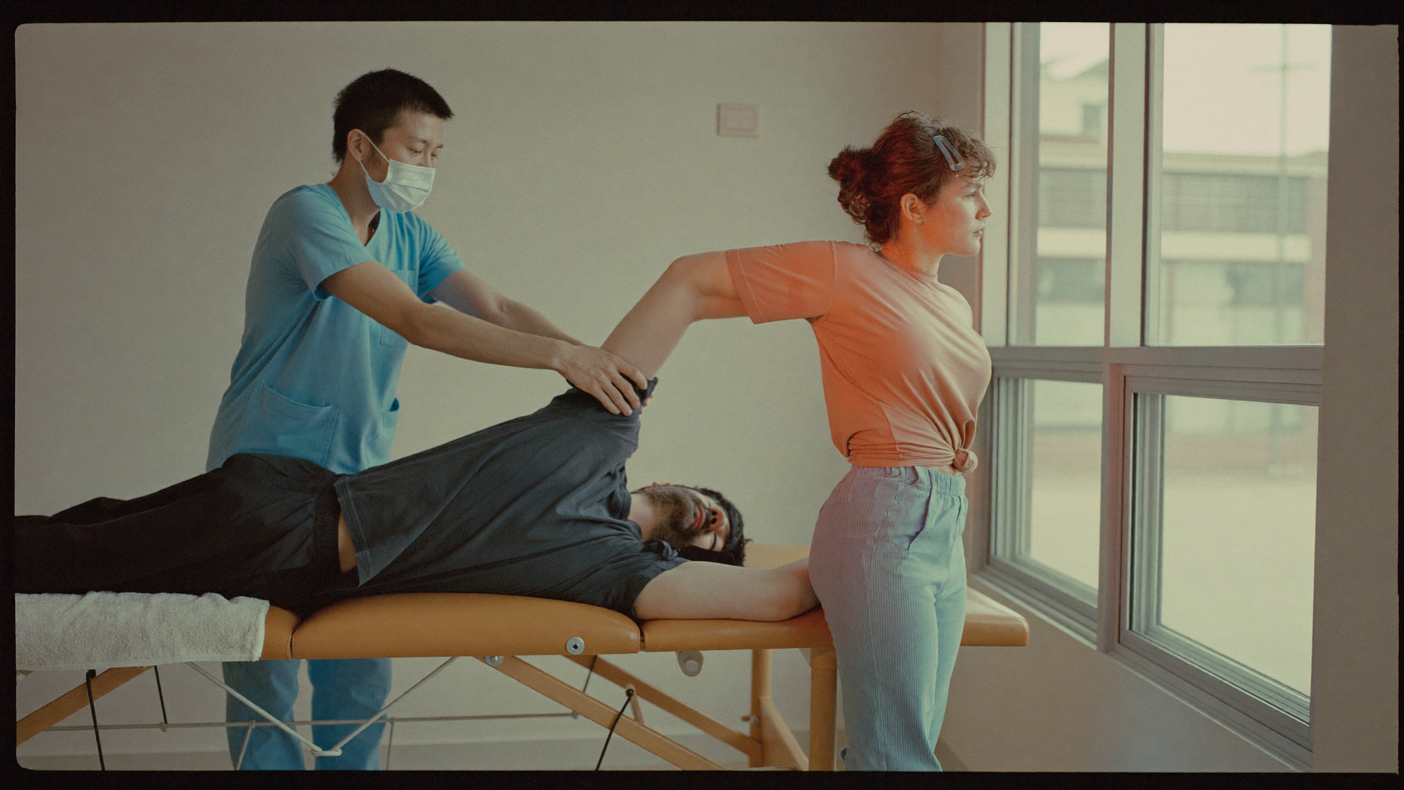 Physical therapist guiding a patient through a shoulder stretch in a physical therapy clinic treatment room
