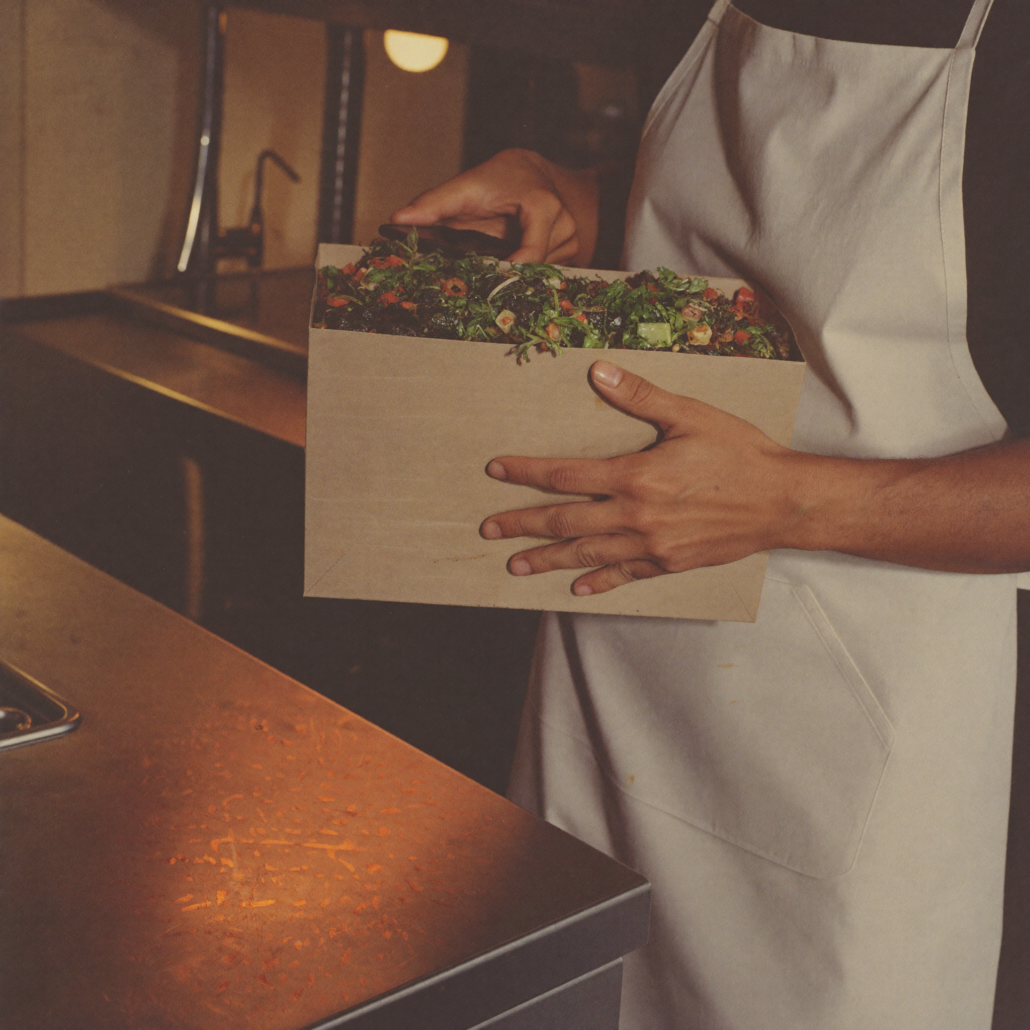 Fast food restaurant employee packing a fresh order into a paper bag at the counter