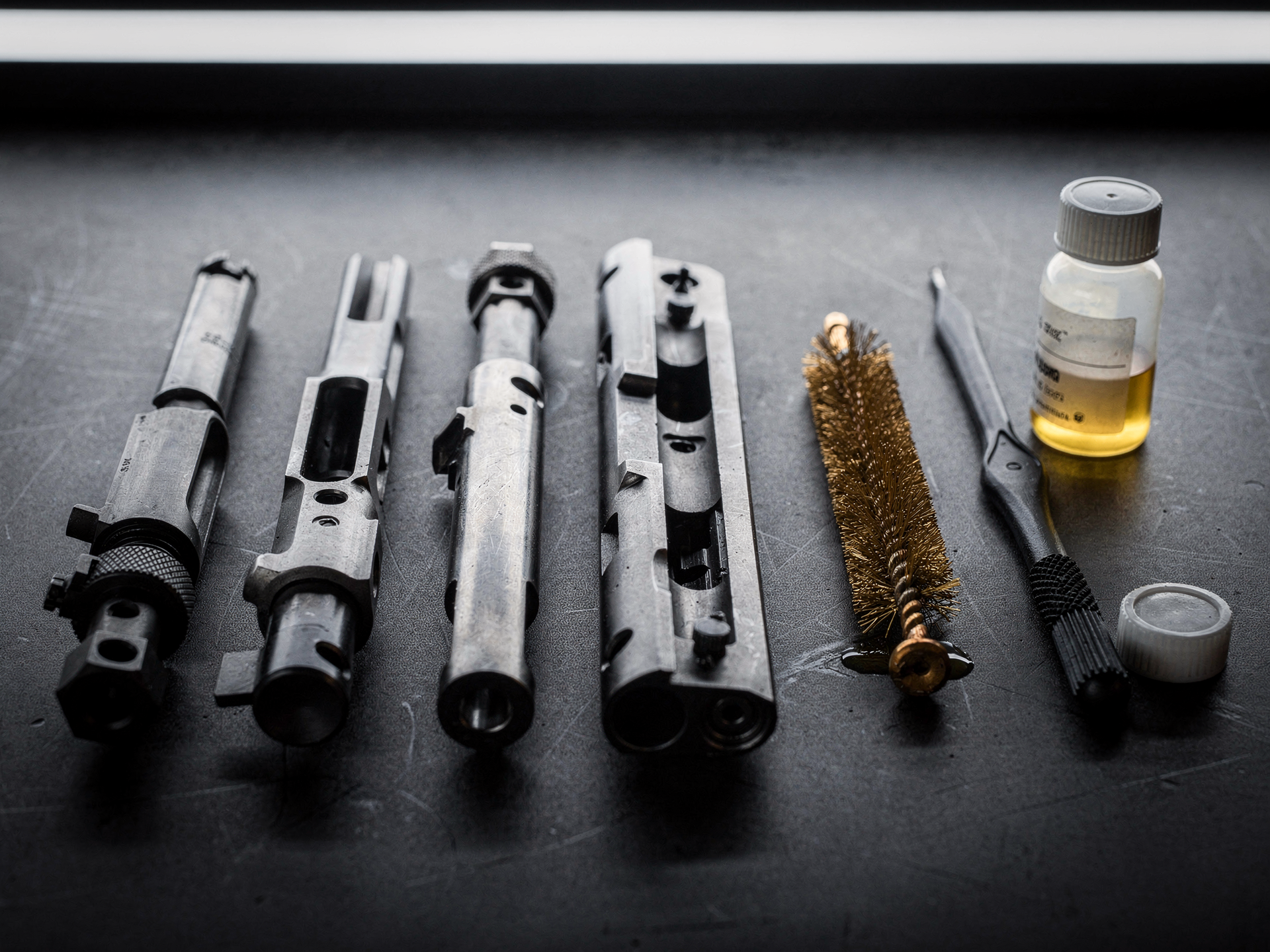 Cleaned bolt carrier components laid out with brushes and oil