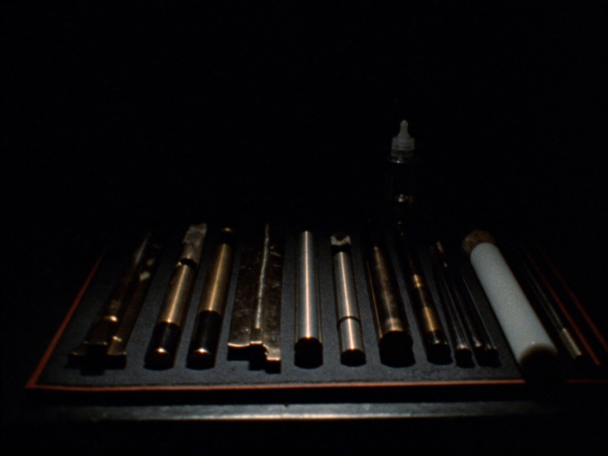 Cleaning rods, brushes and gun oil laid out on a dark bench mat