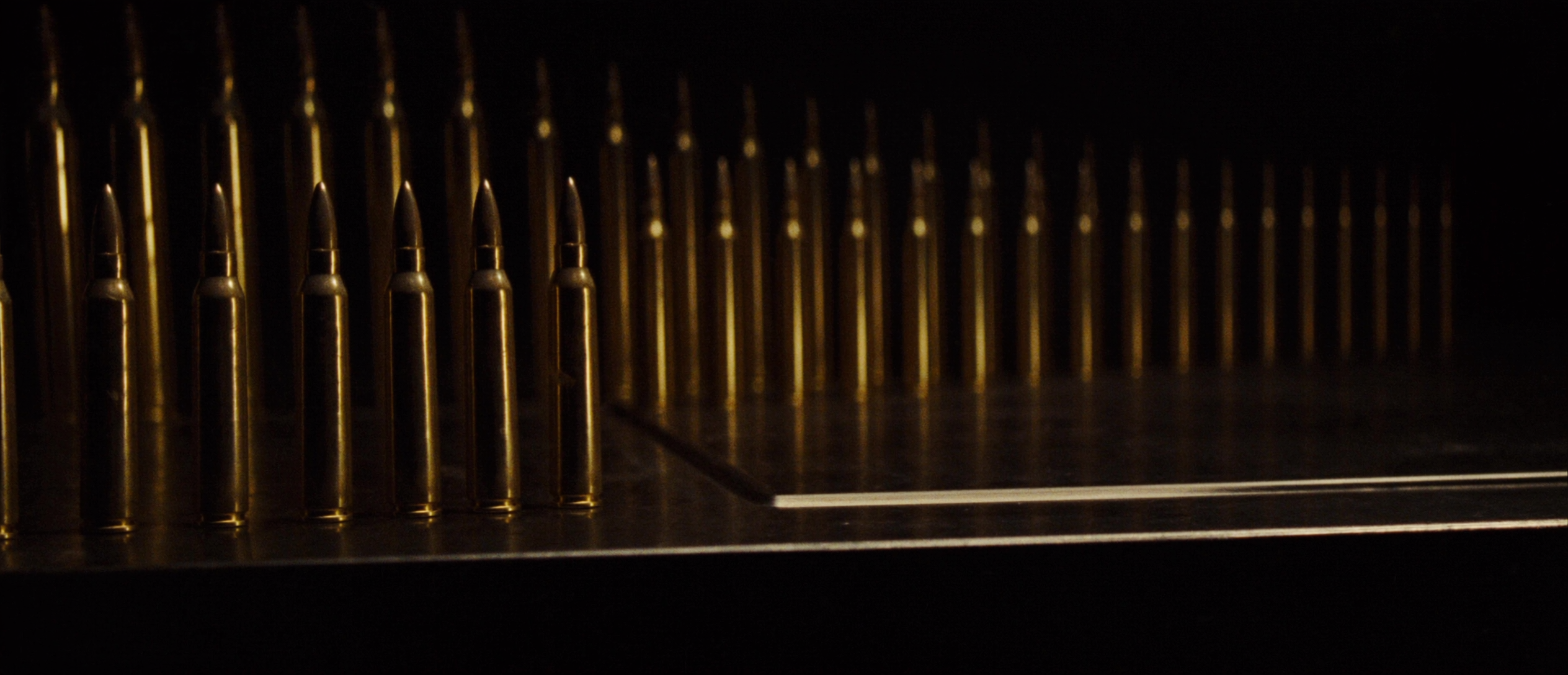 Brass cartridges standing on a dark steel surface in warm light
