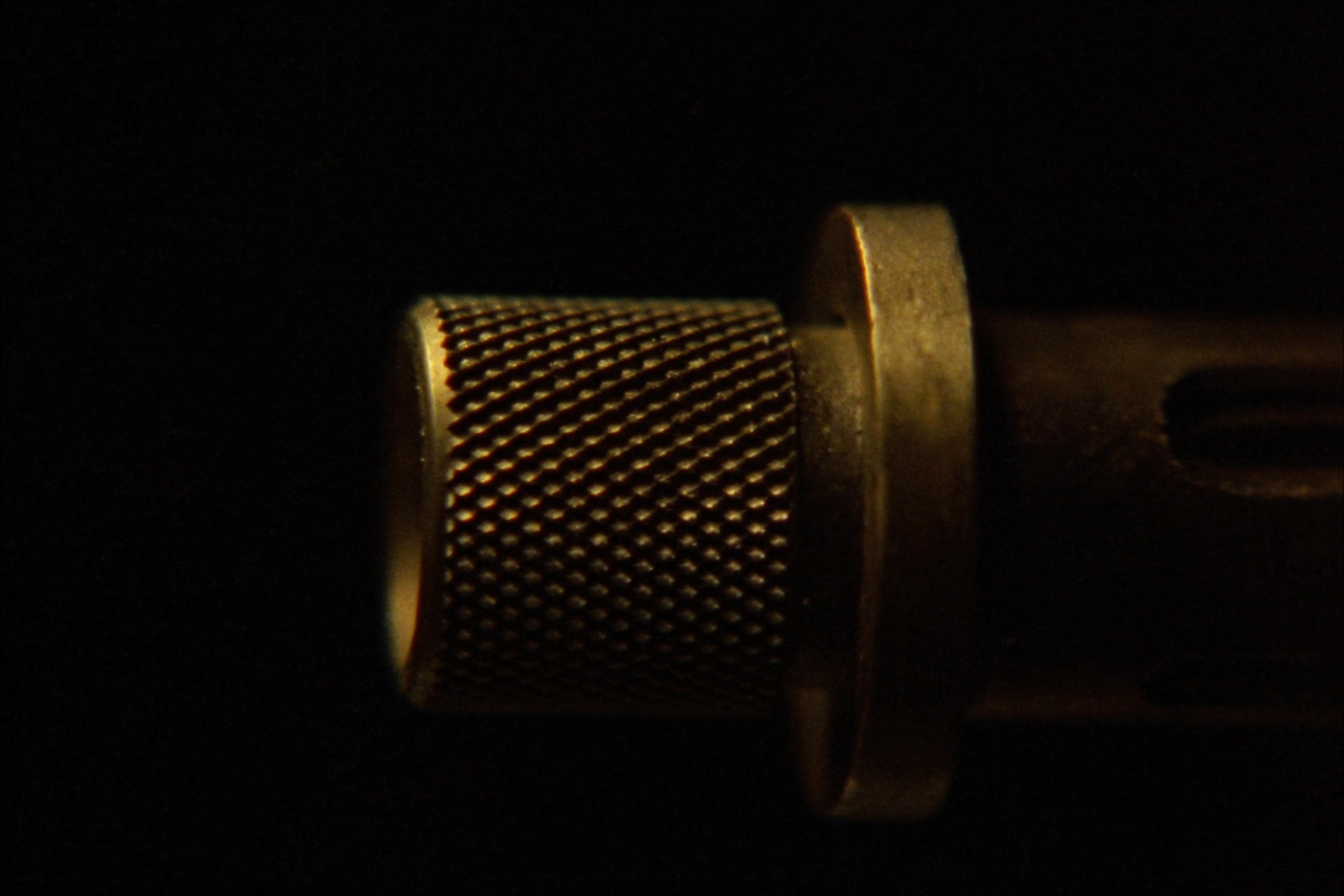 Macro view of a threaded barrel muzzle and knurled thread protector