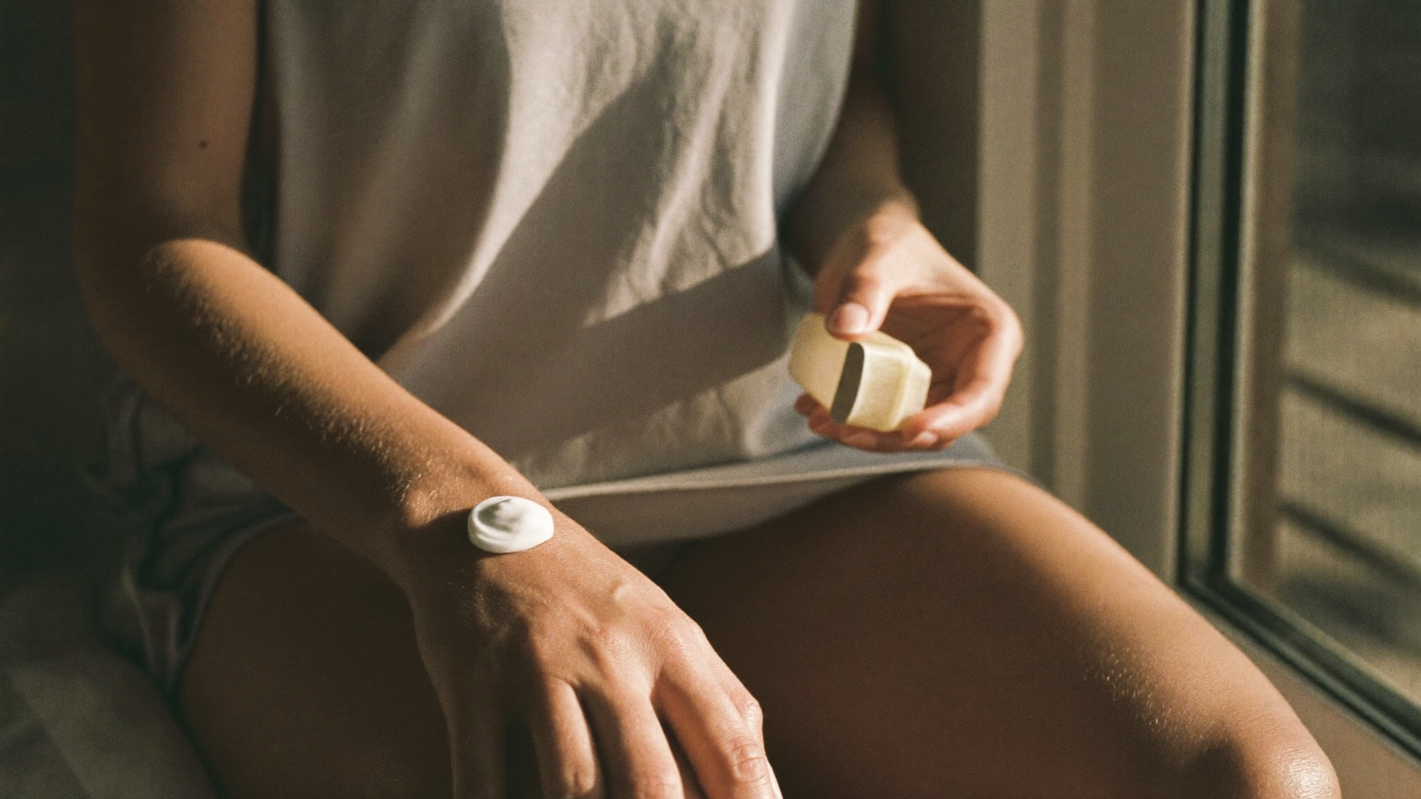 Person calmly applying balm to the back of their hand in morning light