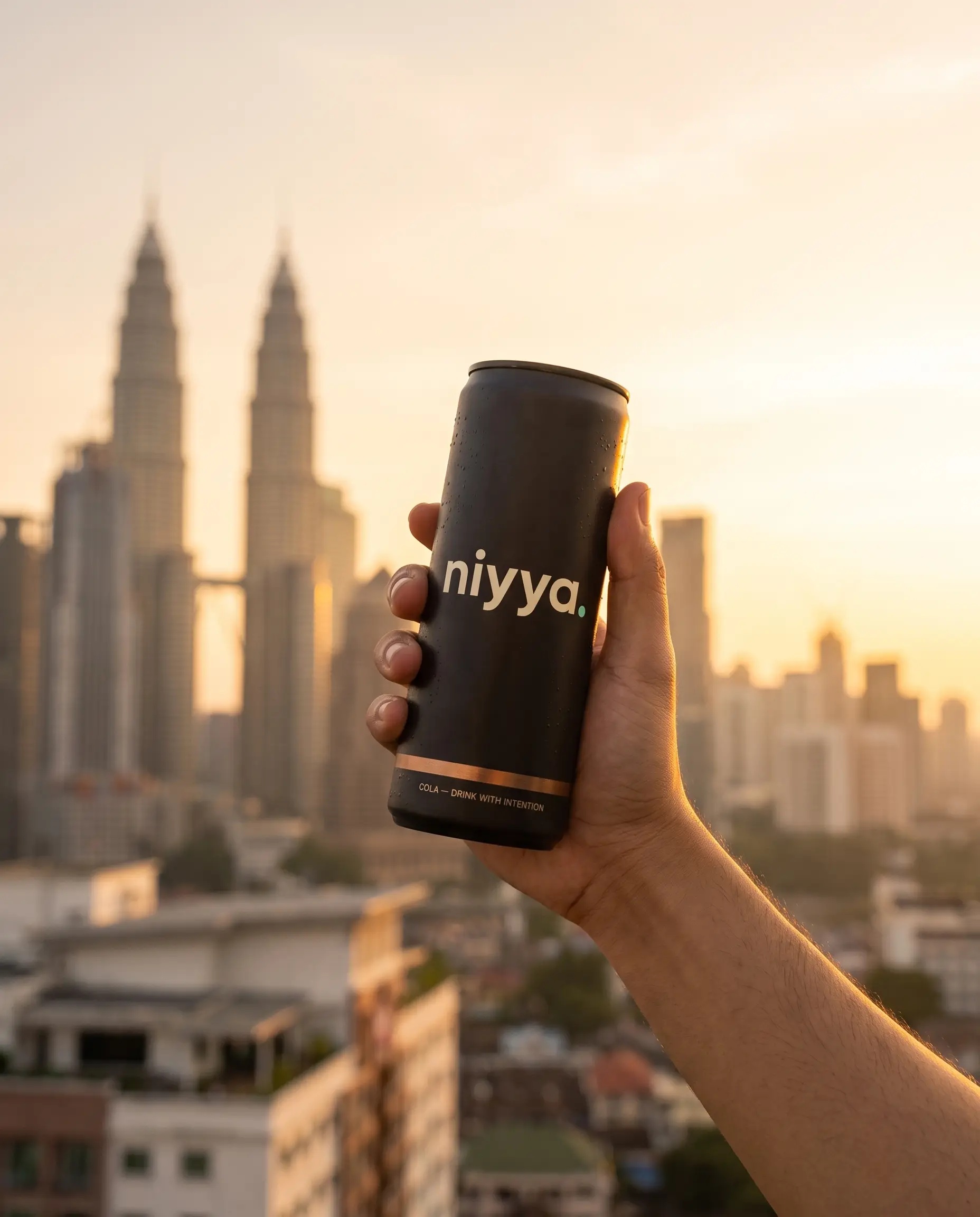 hand raising a niyya cola can over the Kuala Lumpur skyline