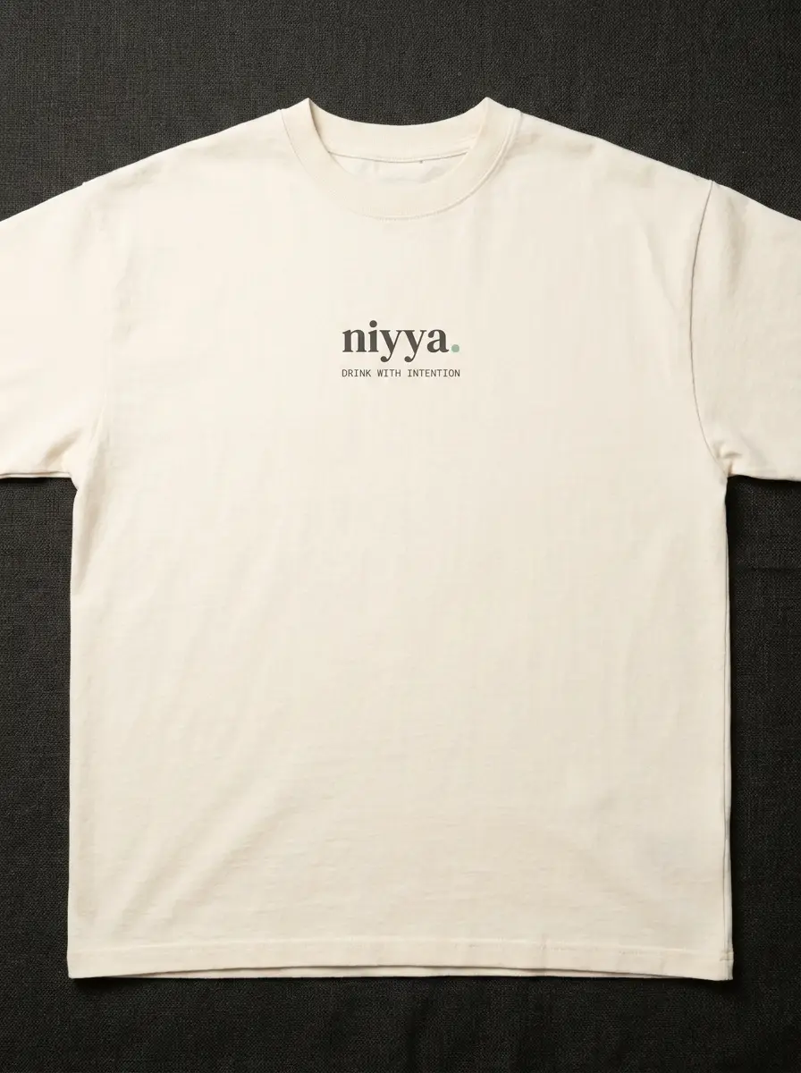 cream heavyweight niyya t-shirt with small chest wordmark, flat-lay on charcoal