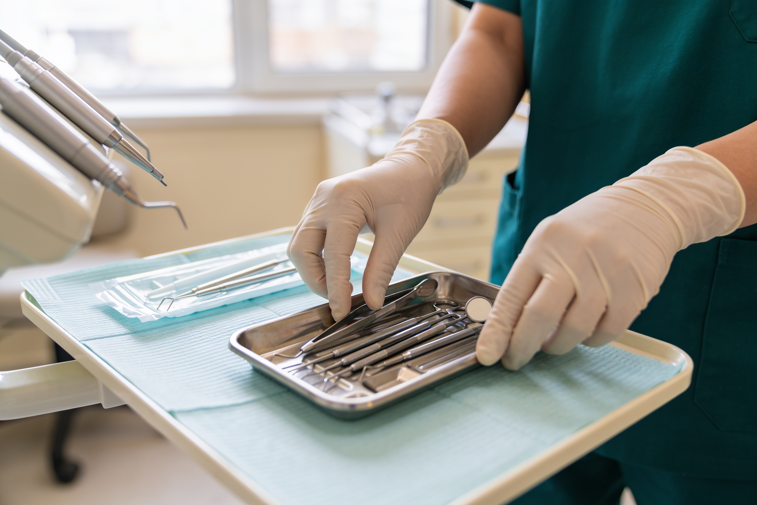 A hygienist laying out clean instruments on a tray