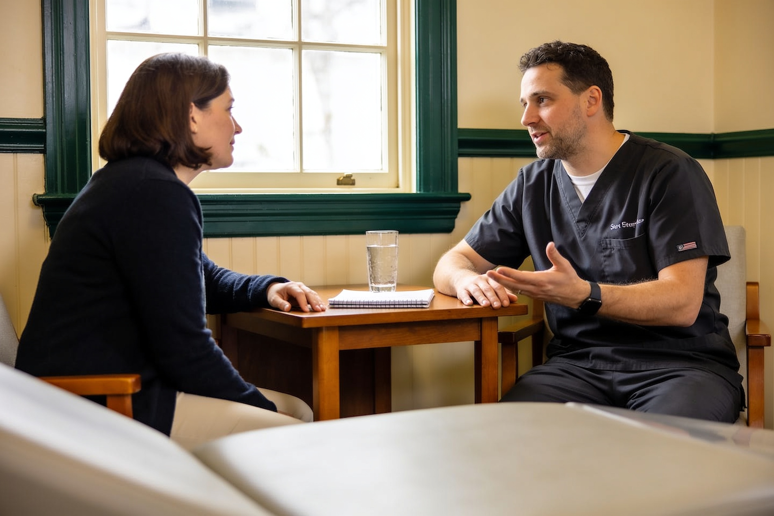 A dentist talking with a patient across a consultation desk