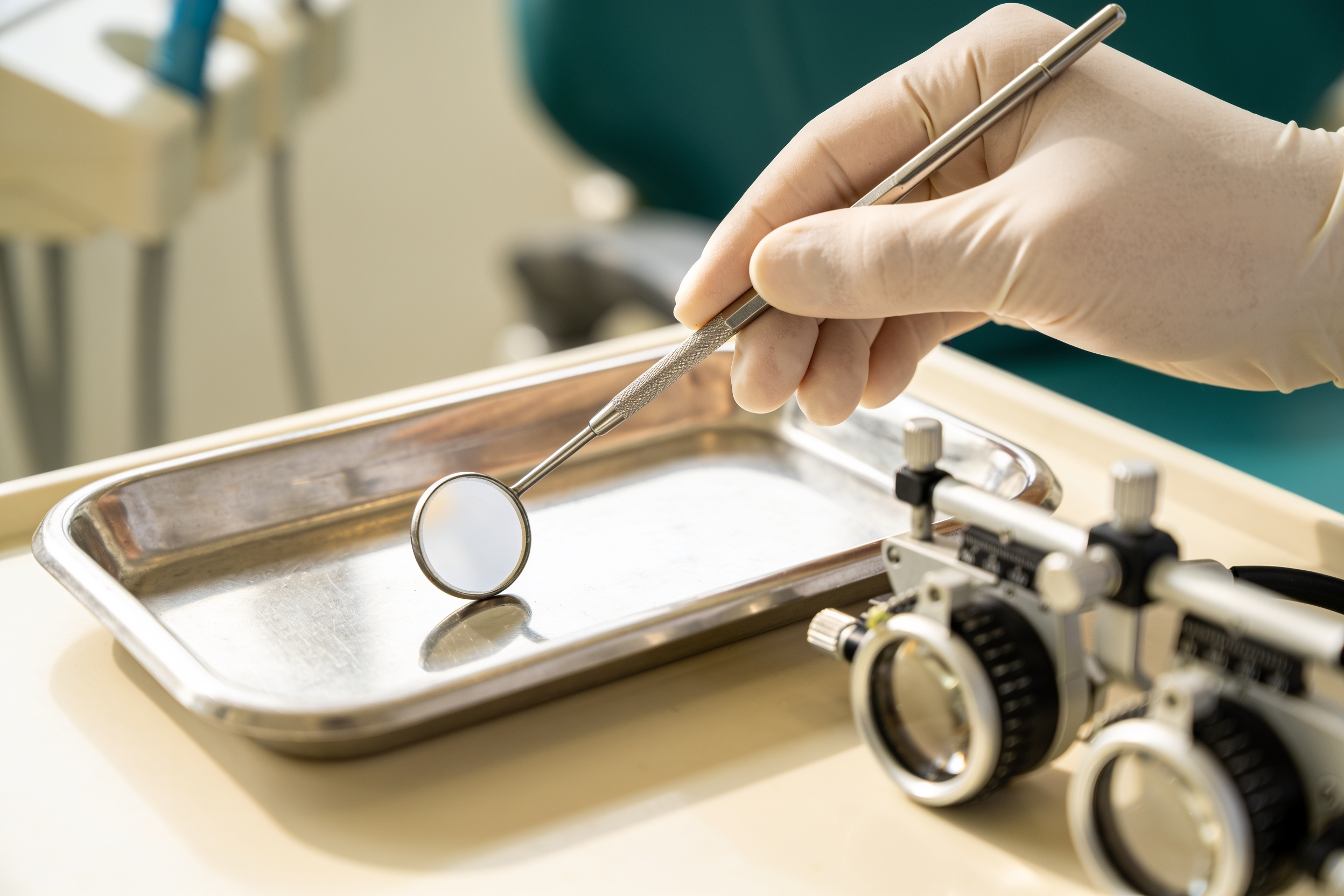 A dental mirror and magnifying loupes on a clean tray