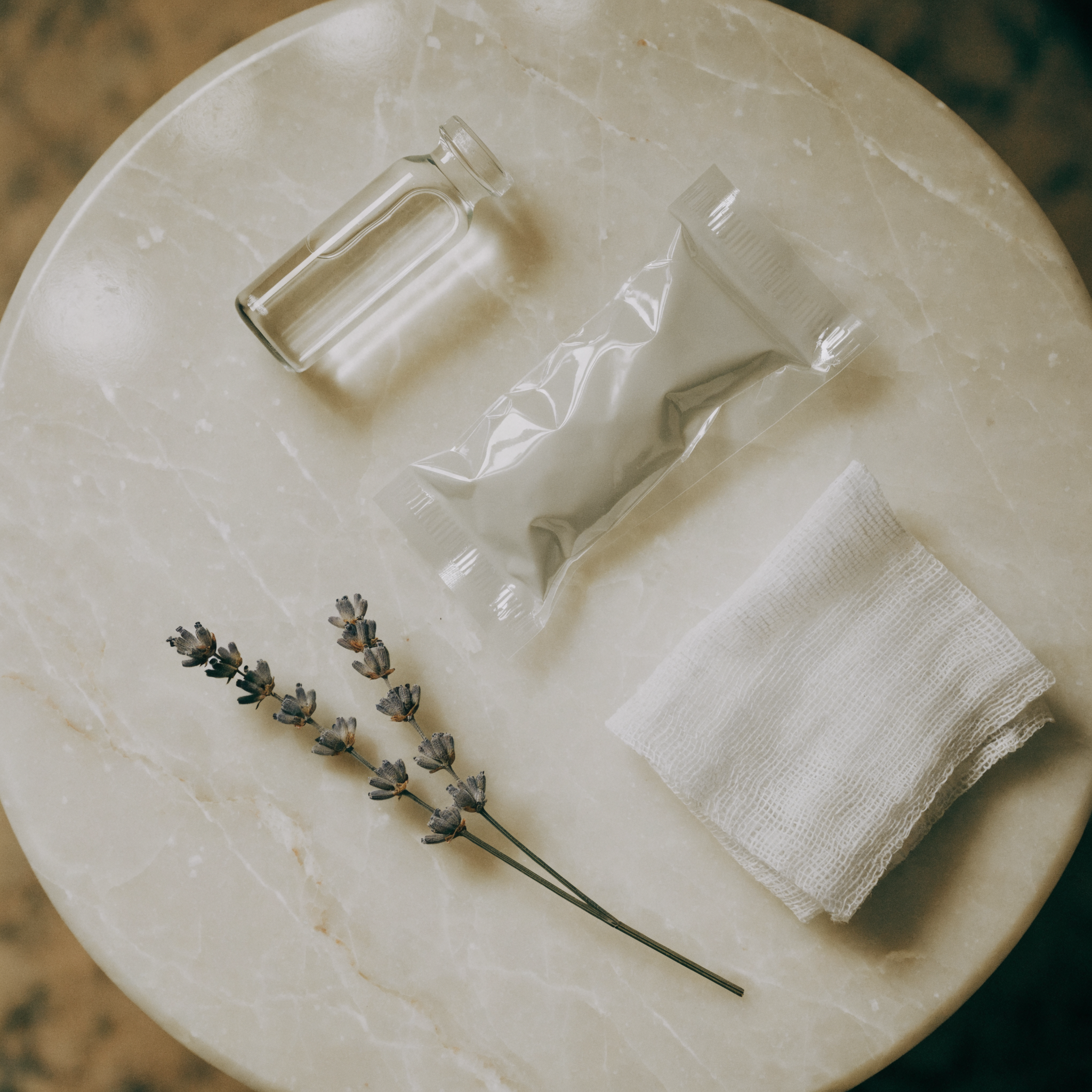 A marble flat lay with a small vial and sprigs of lavender