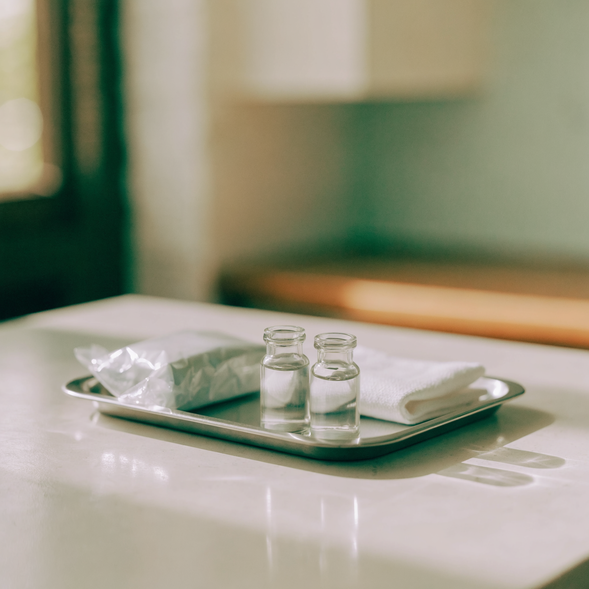 A stainless tray holding a sealed package and two small vials