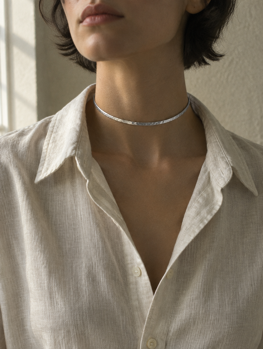 A slim hammered silver choker worn close at the neck
