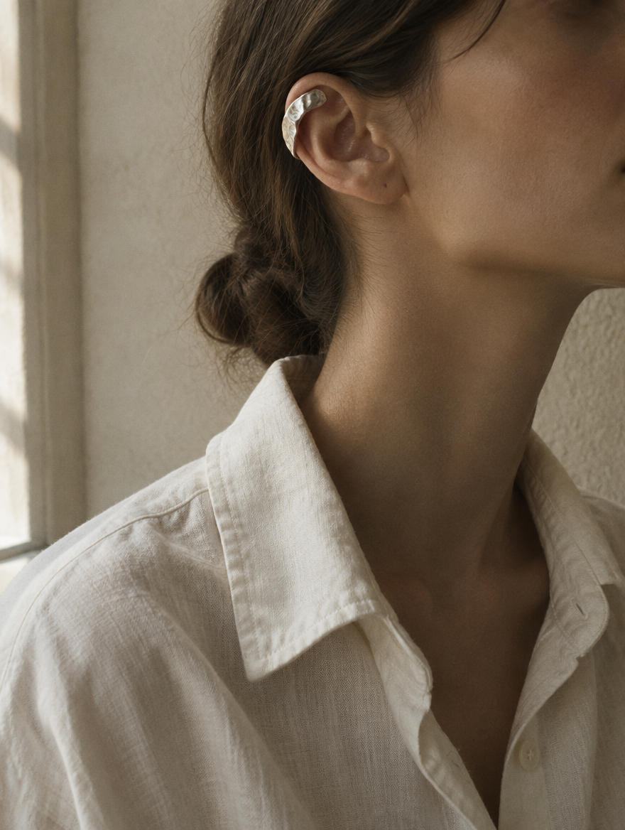 A sculptural hammered silver ear cuff along the upper ear