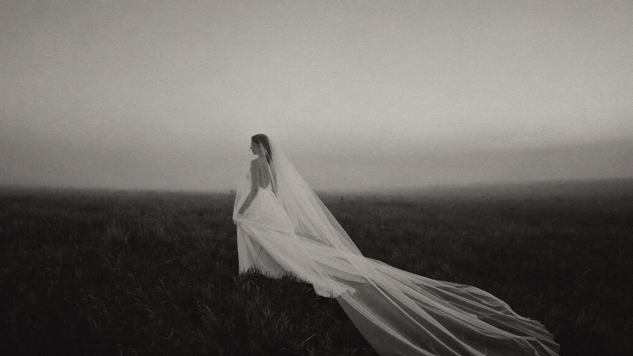 Bride in a flowing gown walking through a misty meadow