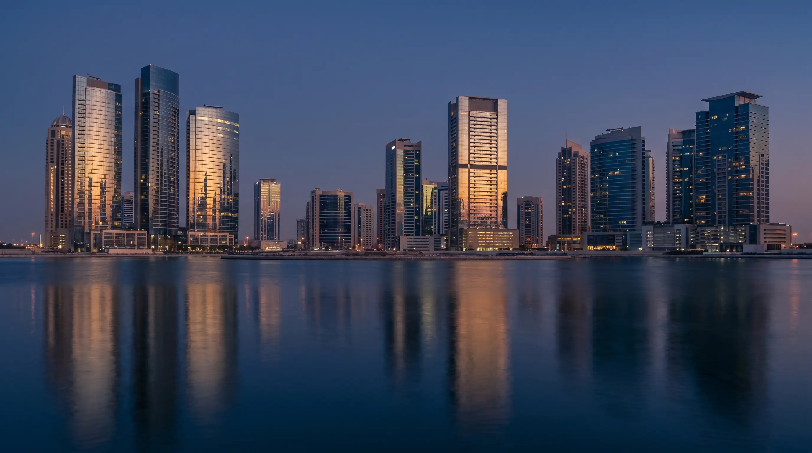 Gulf financial district skyline at blue hour with calm water reflection