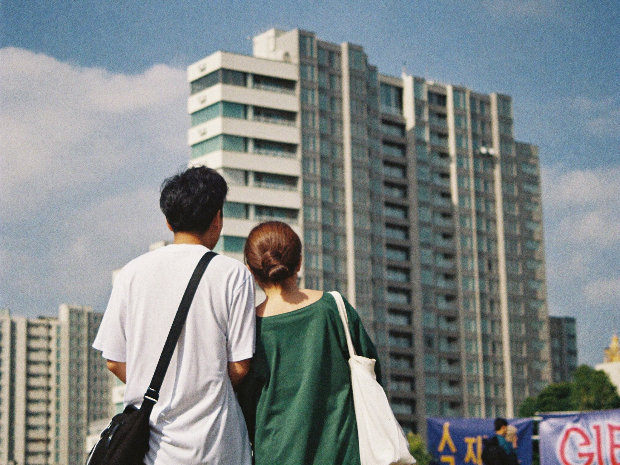 신축 아파트 단지를 올려다보는 중년 부부의 뒷모습