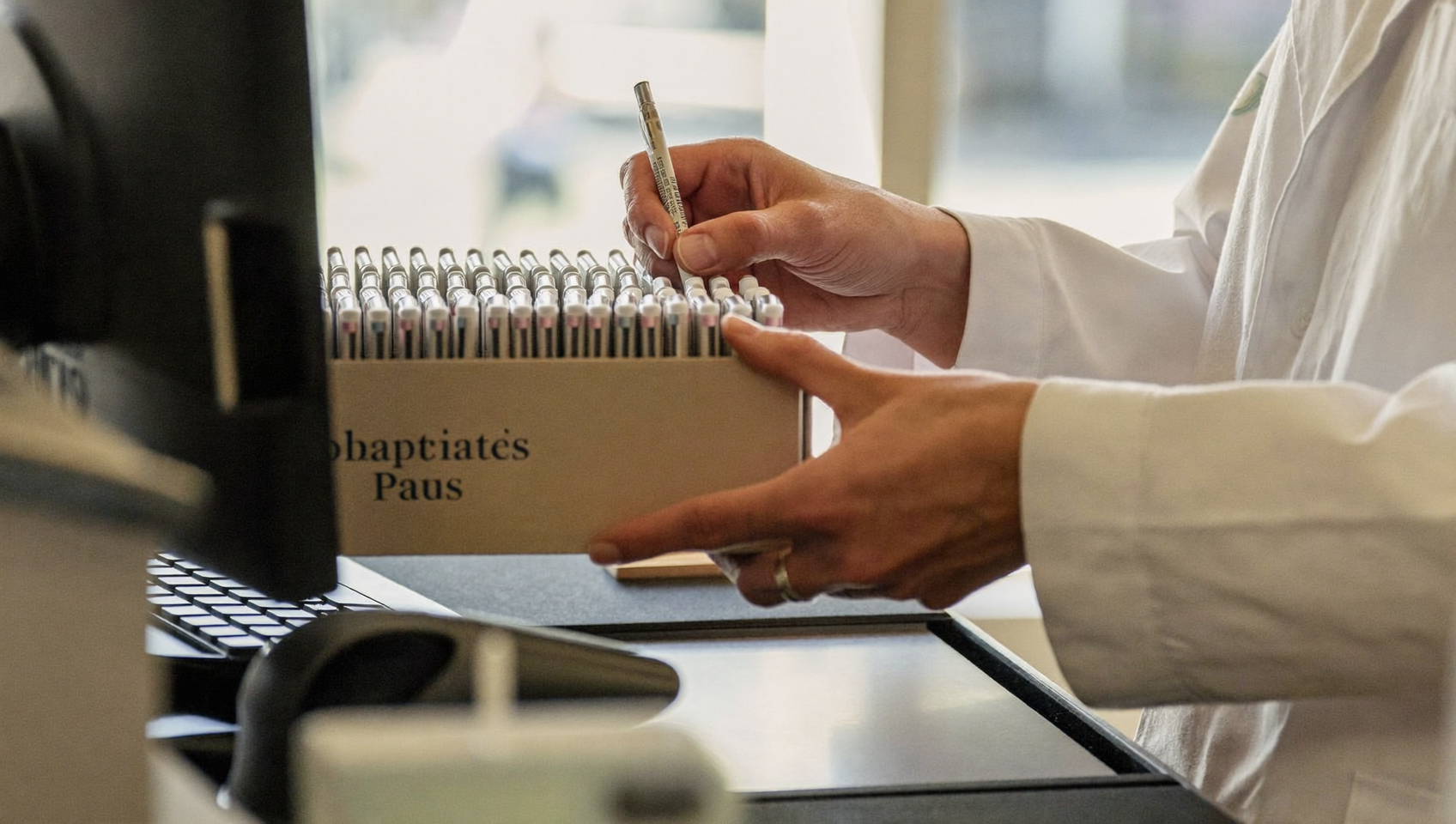 Pharmacist ringing up a box of insulin pens at a pharmacy checkout counter