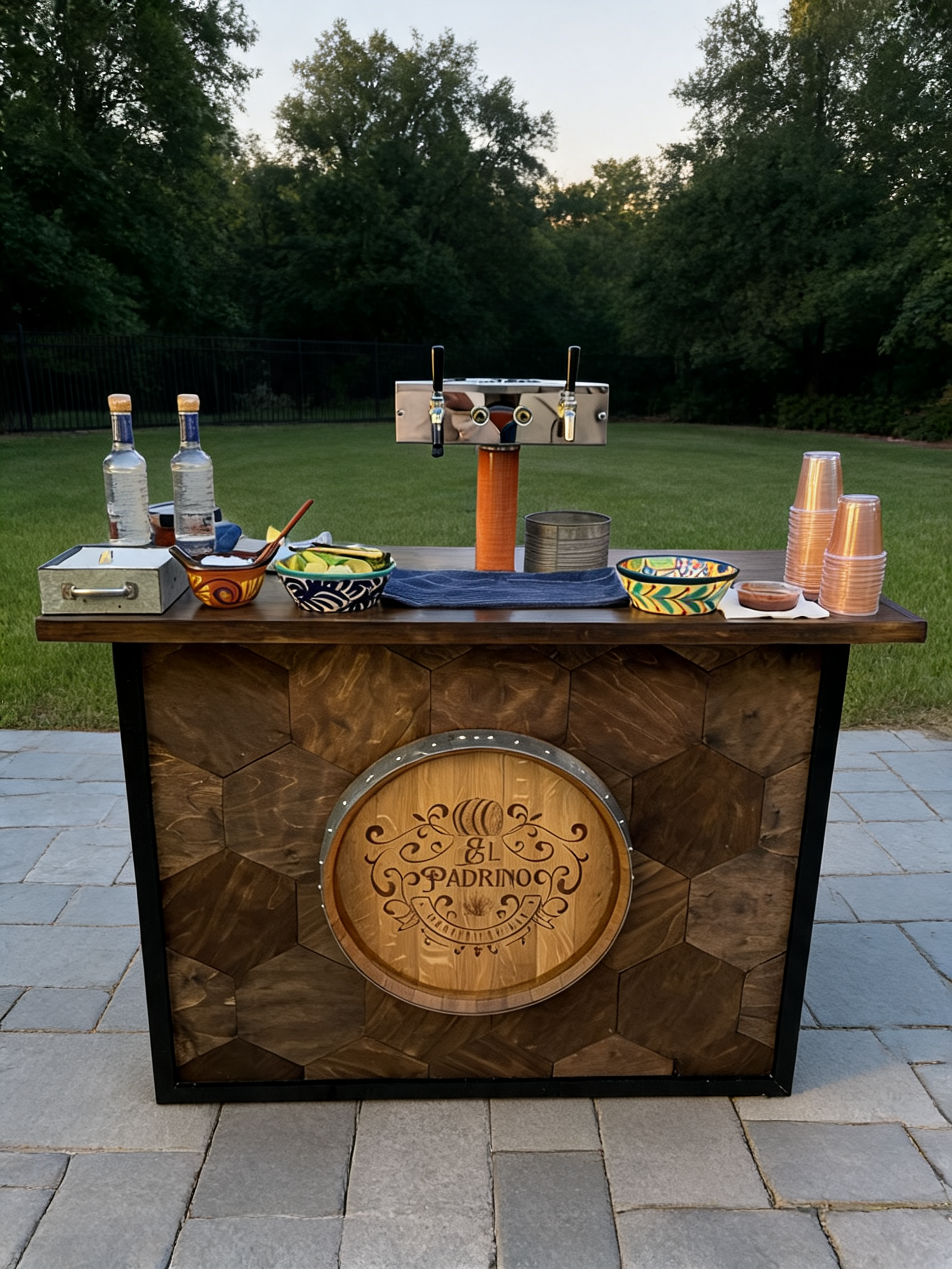 The El Padrino handcrafted barrel bar set up on a stone patio at a backyard event at dusk