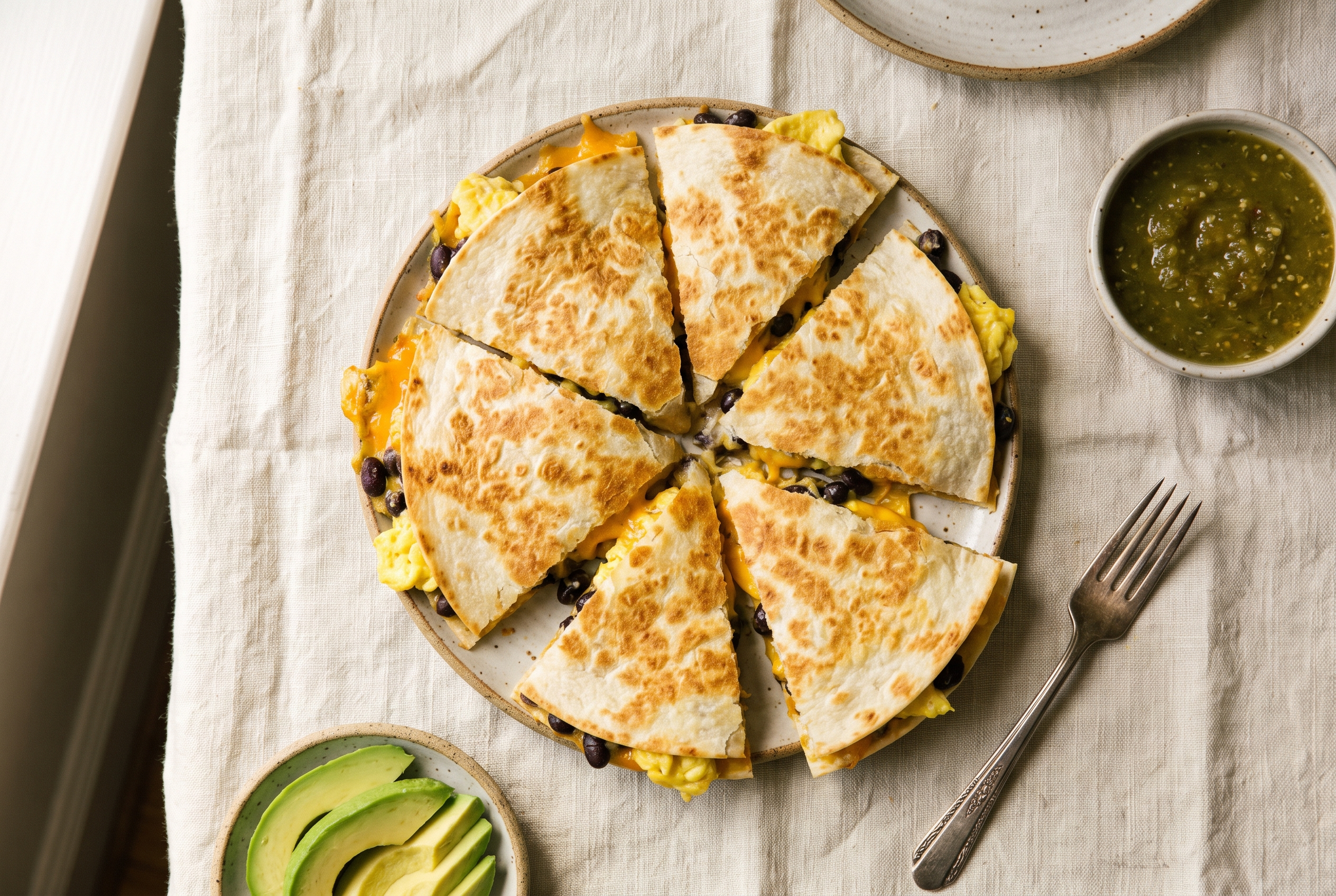 Breakfast quesadilla cut into wedges showing soft scrambled eggs, melted cheddar and black beans inside a crisp golden tortilla, 30g protein quick breakfast recipe