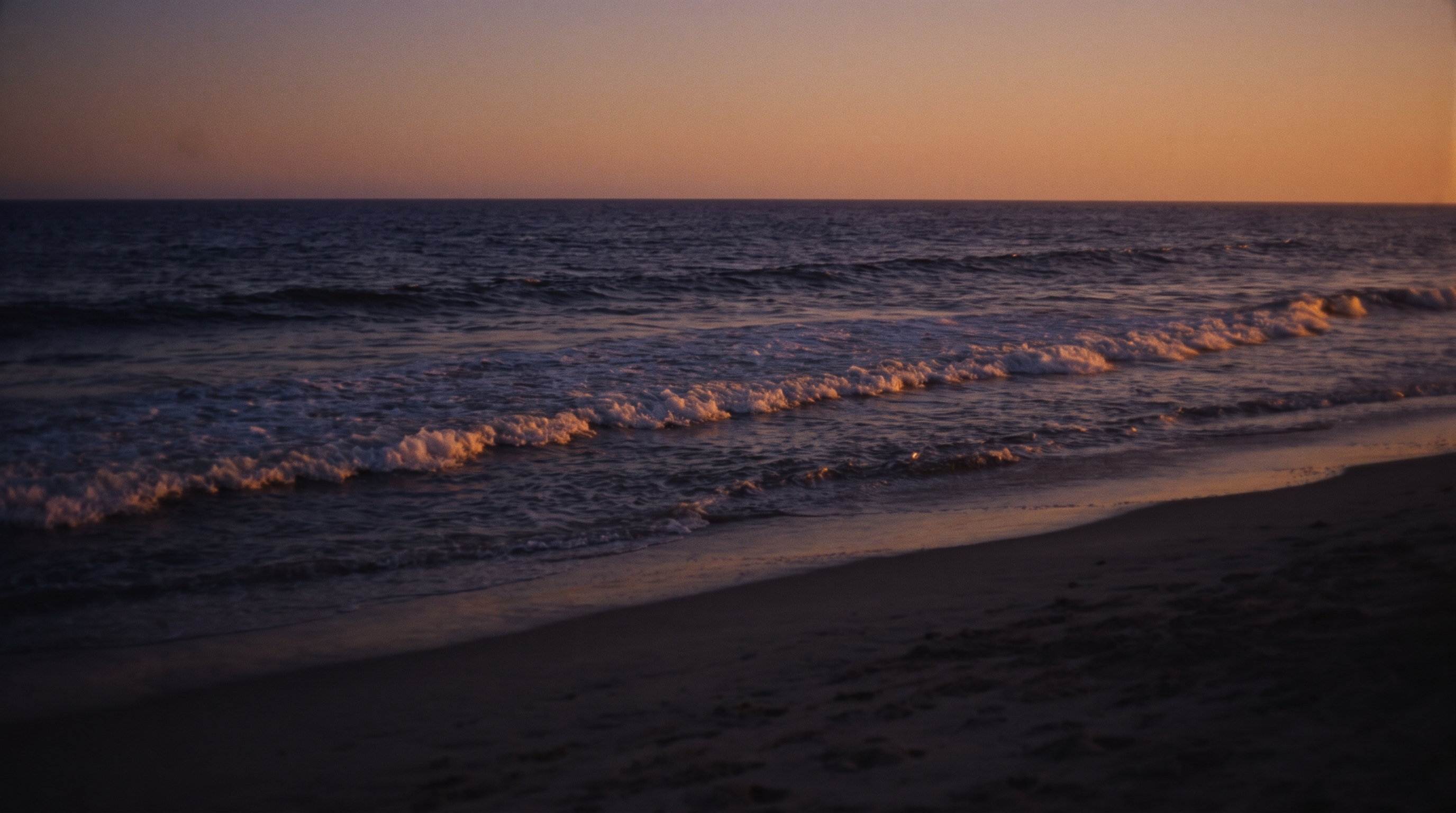 Dusk swell breaking on an empty shore.
