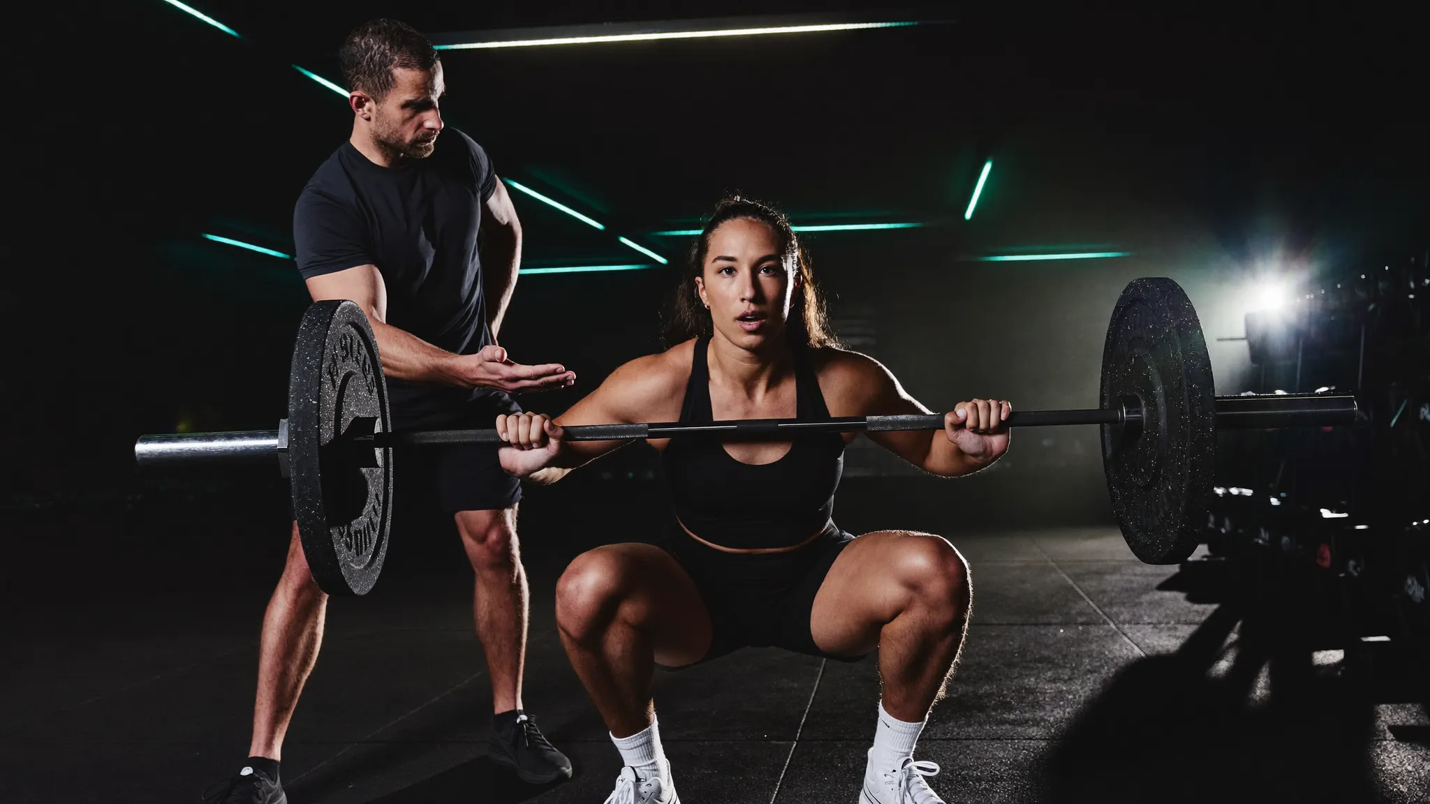 Coach guiding an athlete through a barbell lift