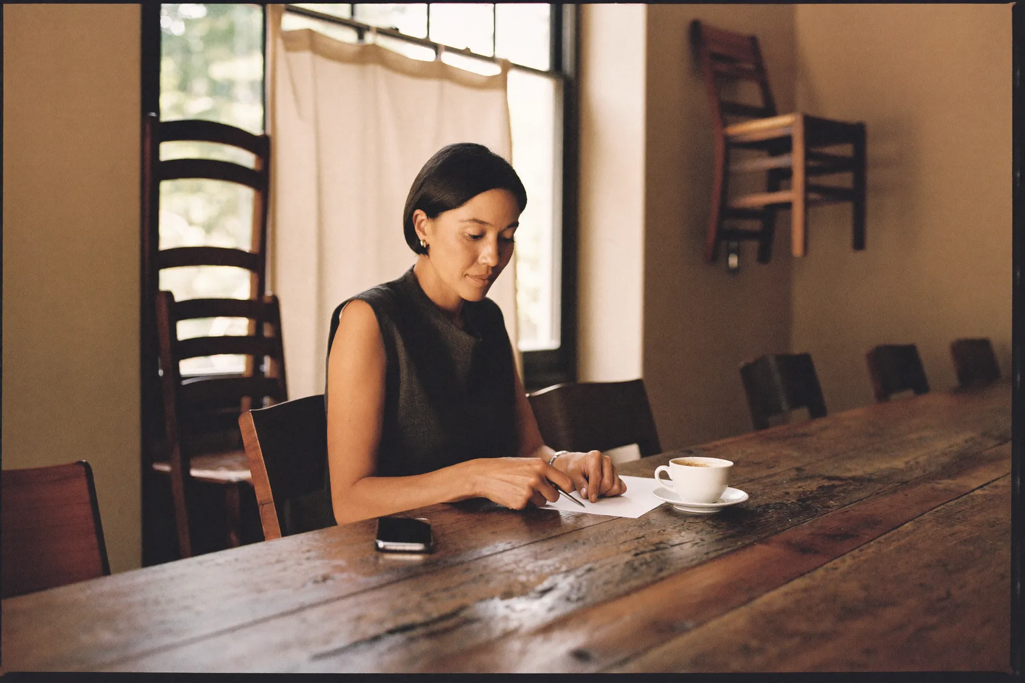 Restaurant owner reviewing paperwork at a table in her closed dining room in the morning