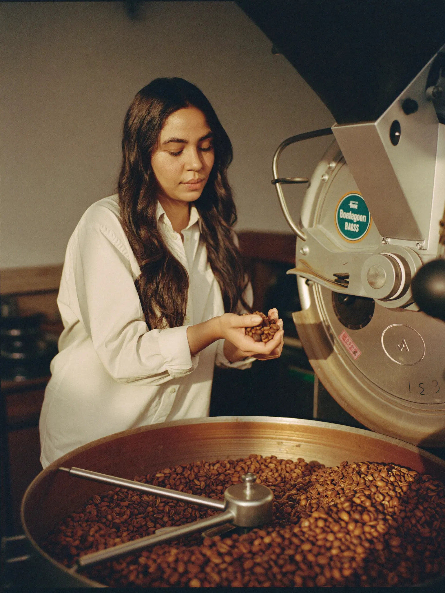 Coffee roaster inspecting freshly roasted beans in an artisan roastery