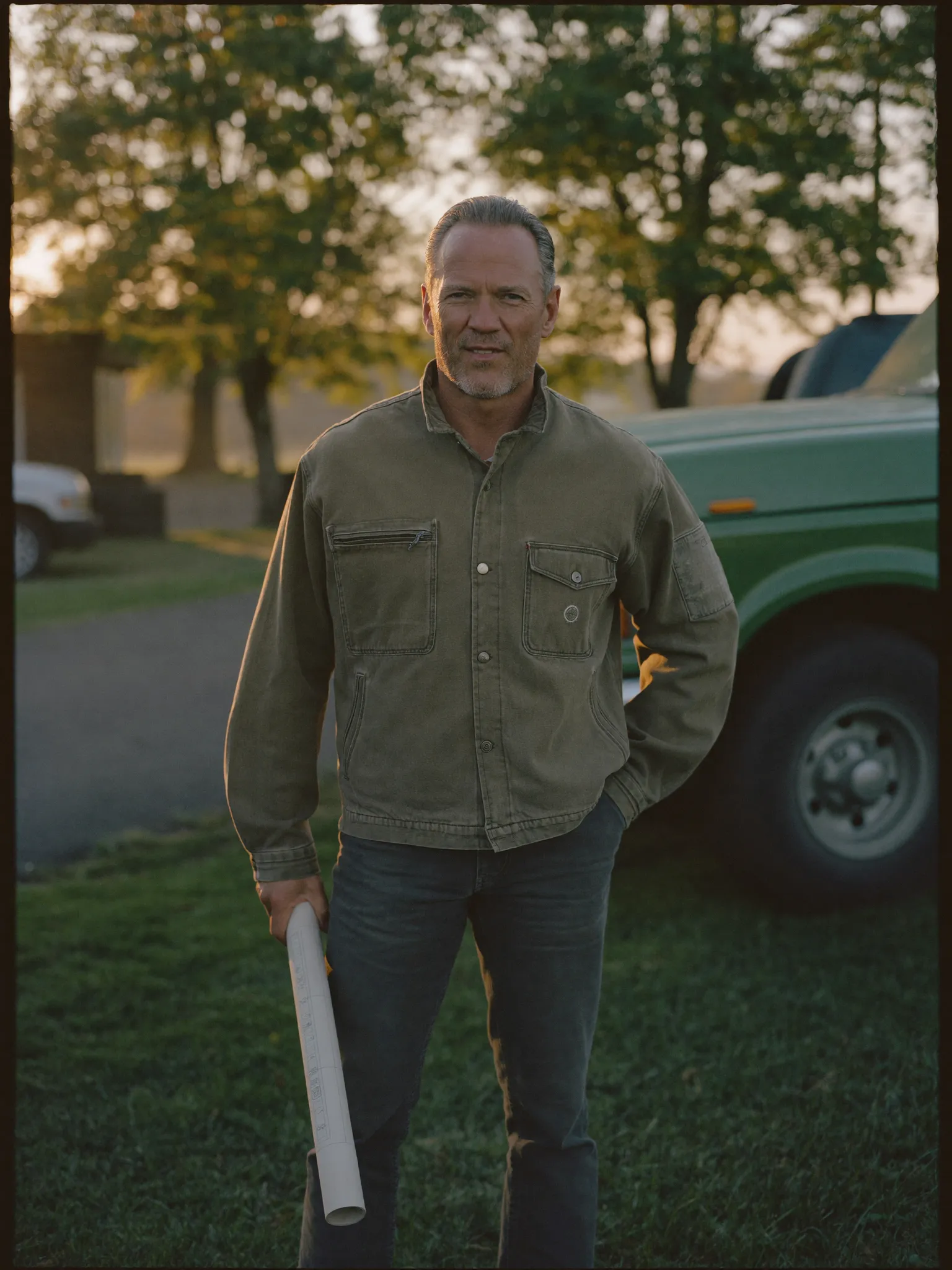 Owner of a landscaping company standing beside his work truck at sunrise