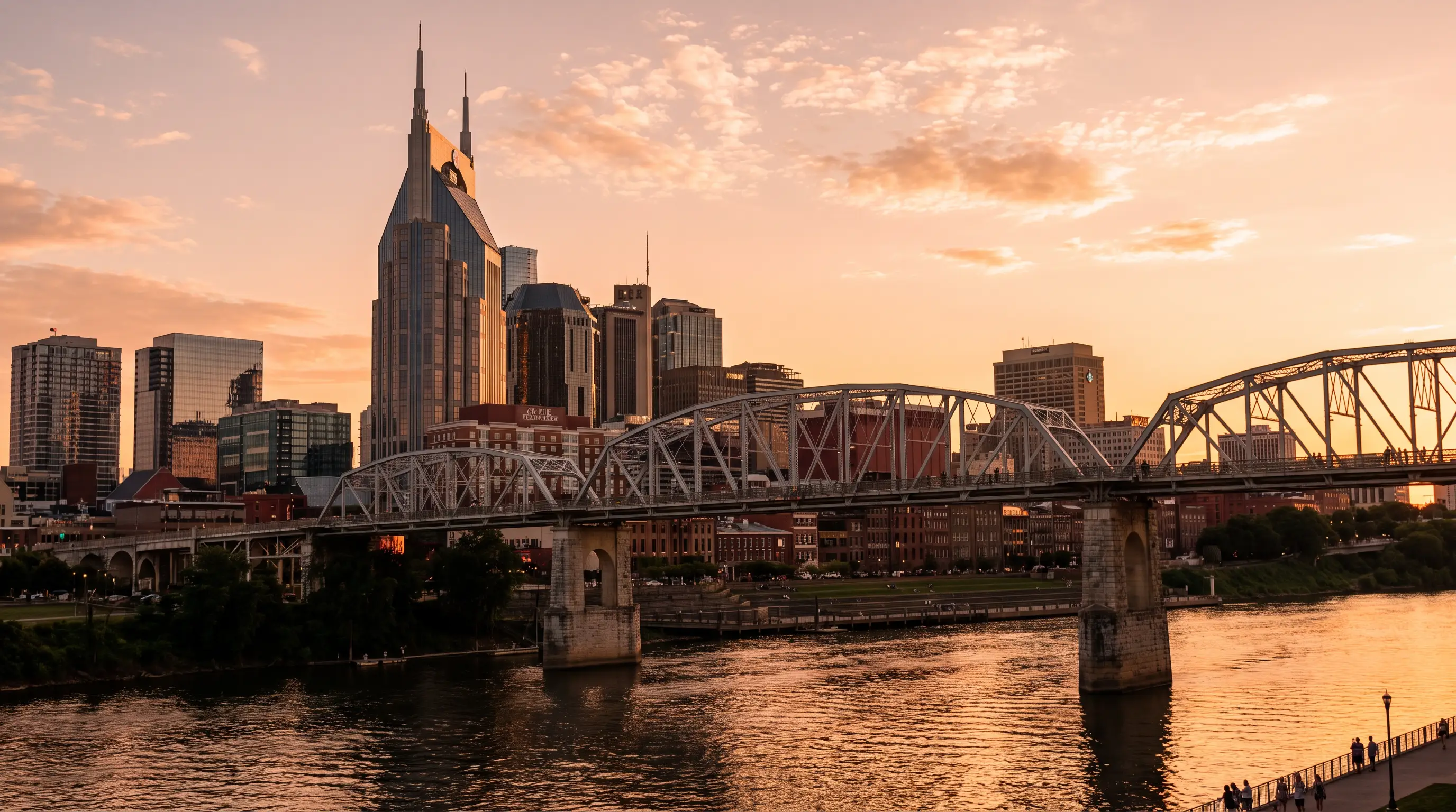 Nashville skyline at golden hour over the Cumberland River with the pedestrian bridge