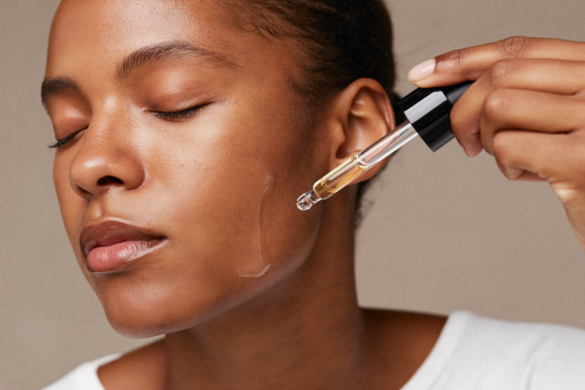 Woman applying a brightening serum with a dropper to fade dark spots