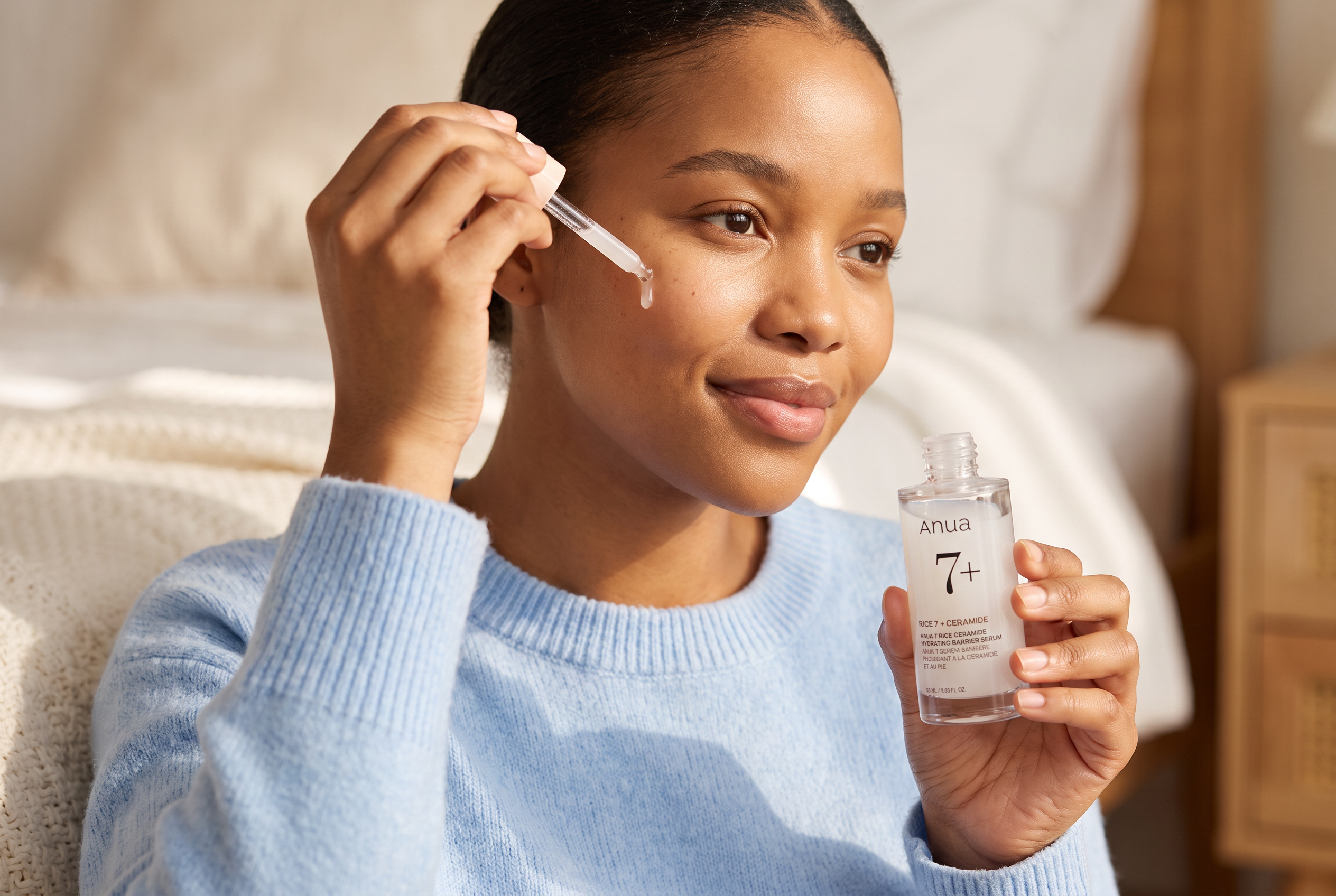 Woman applying Anua 7 Rice Ceramide barrier serum to dry skin