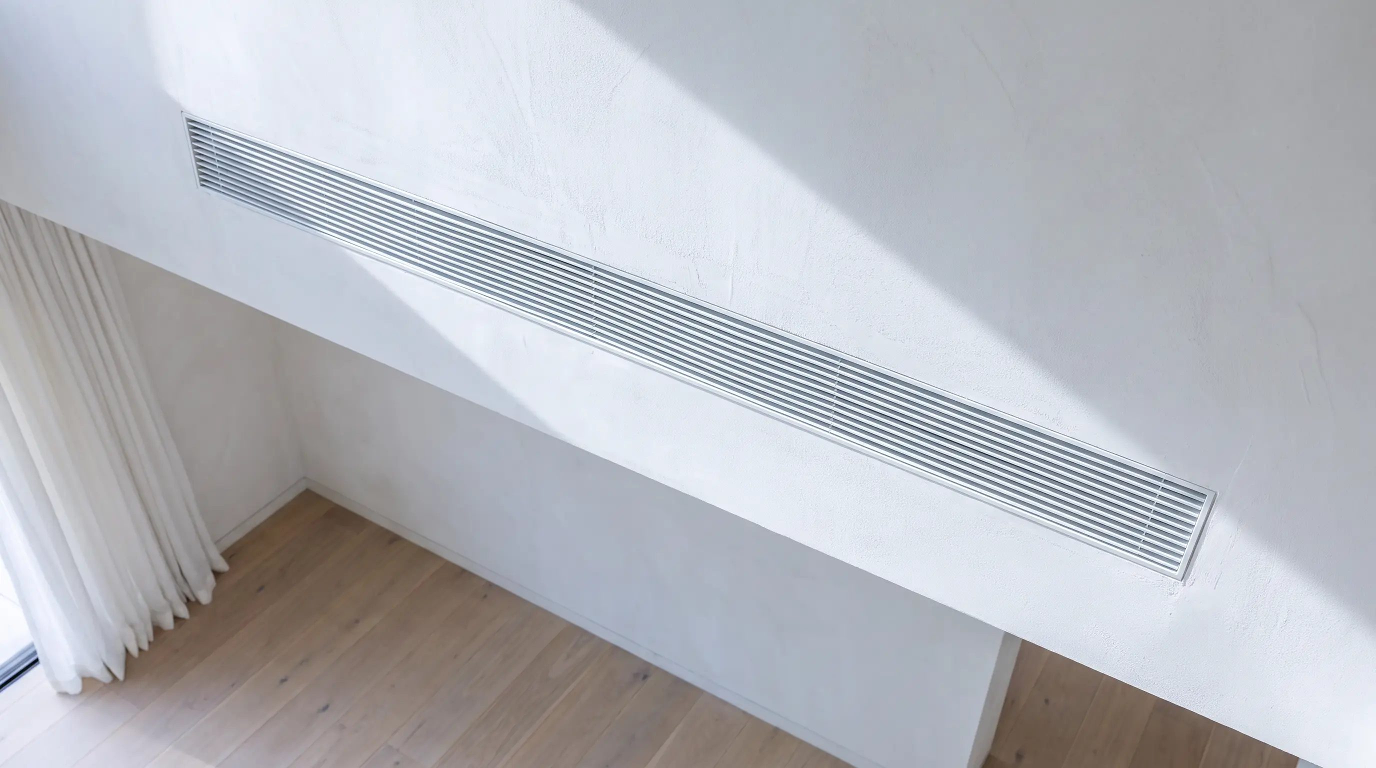 Concealed linear ventilation grille integrated into a plastered ceiling